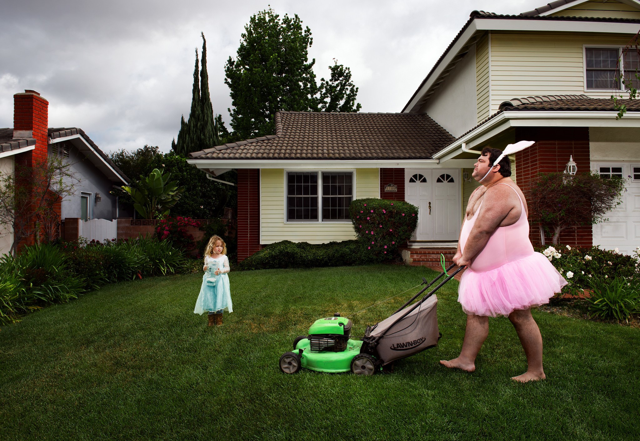 Man in tutu mowing lawn with girl watching HD Wallpaper