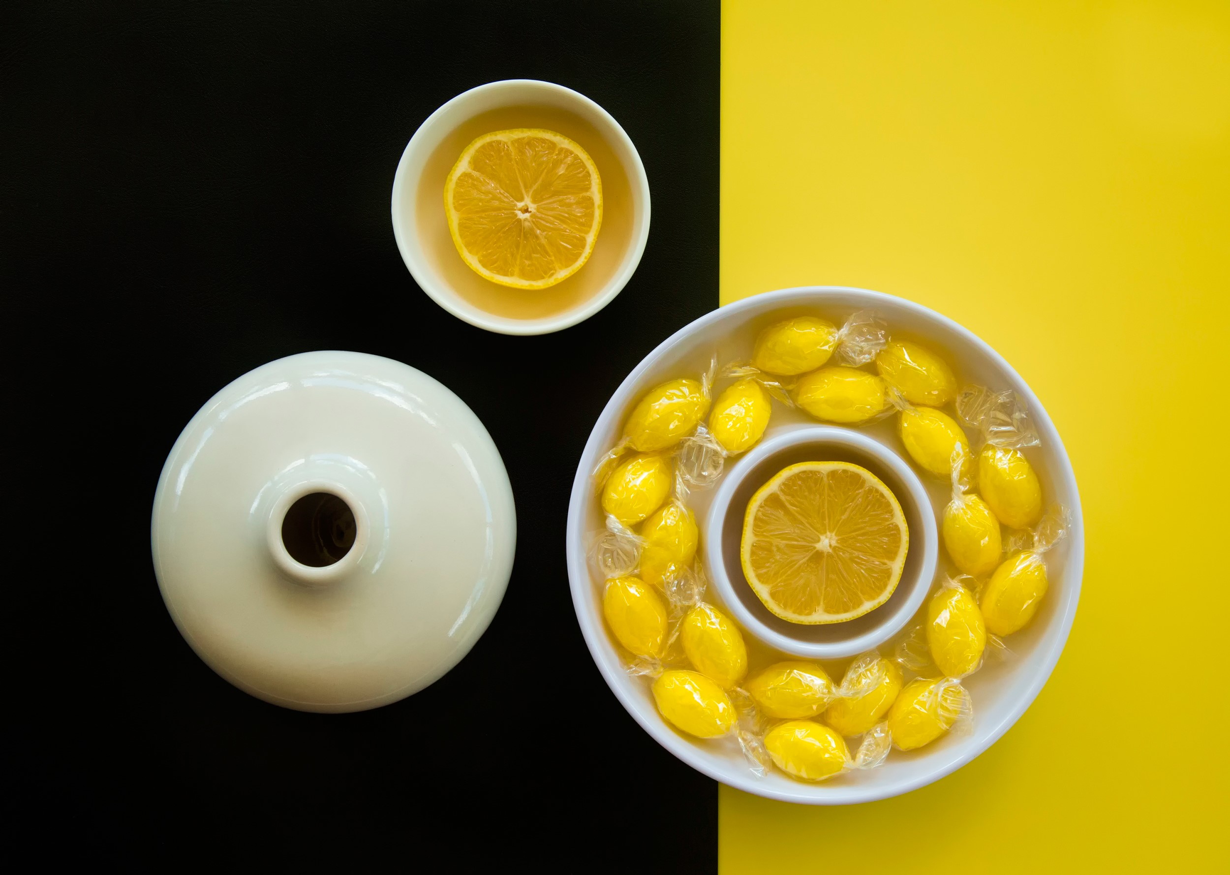 Lemons and candies arranged on a black and yellow background HD Wallpaper