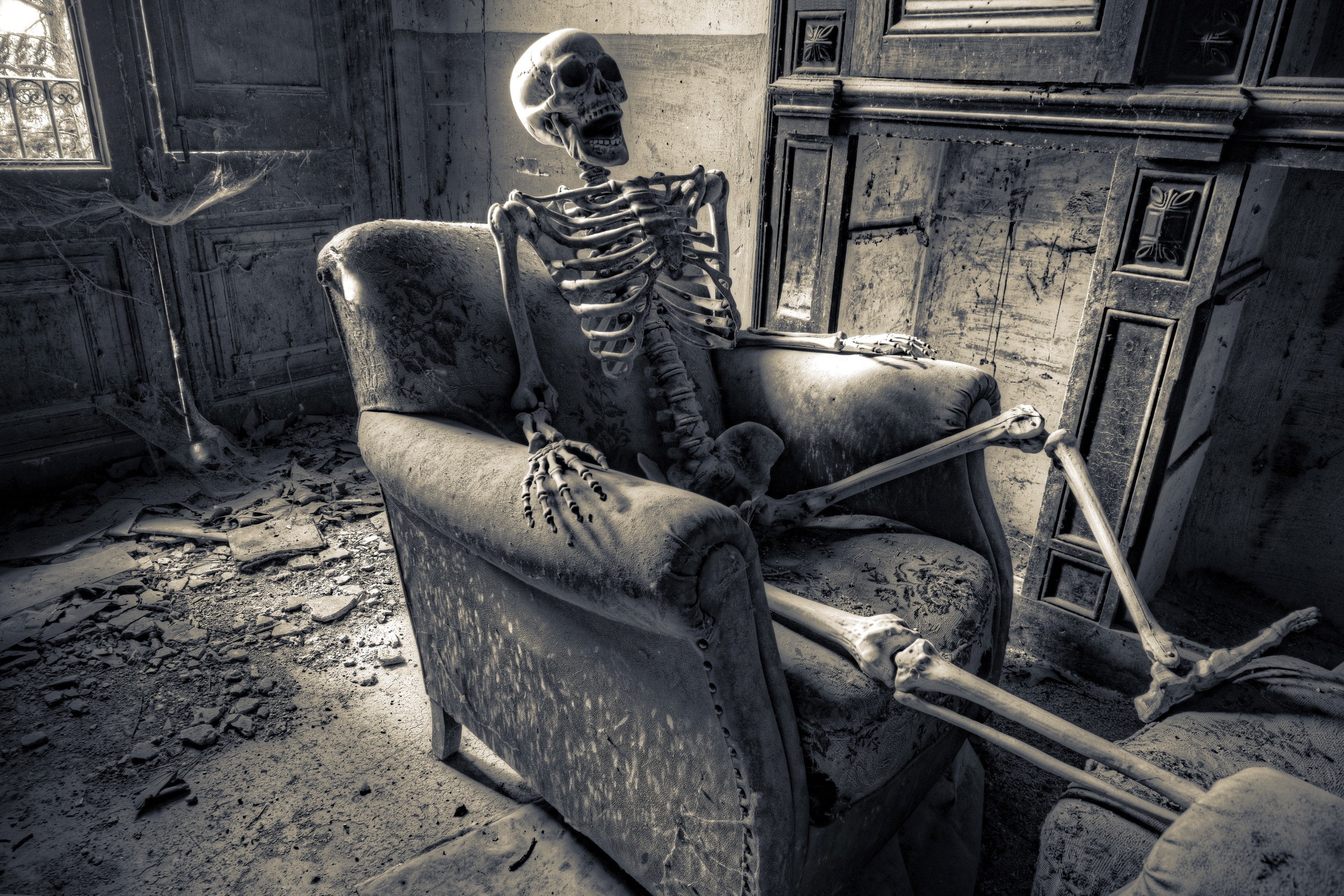Skeleton sitting in an old armchair in a derelict room HD Wallpaper