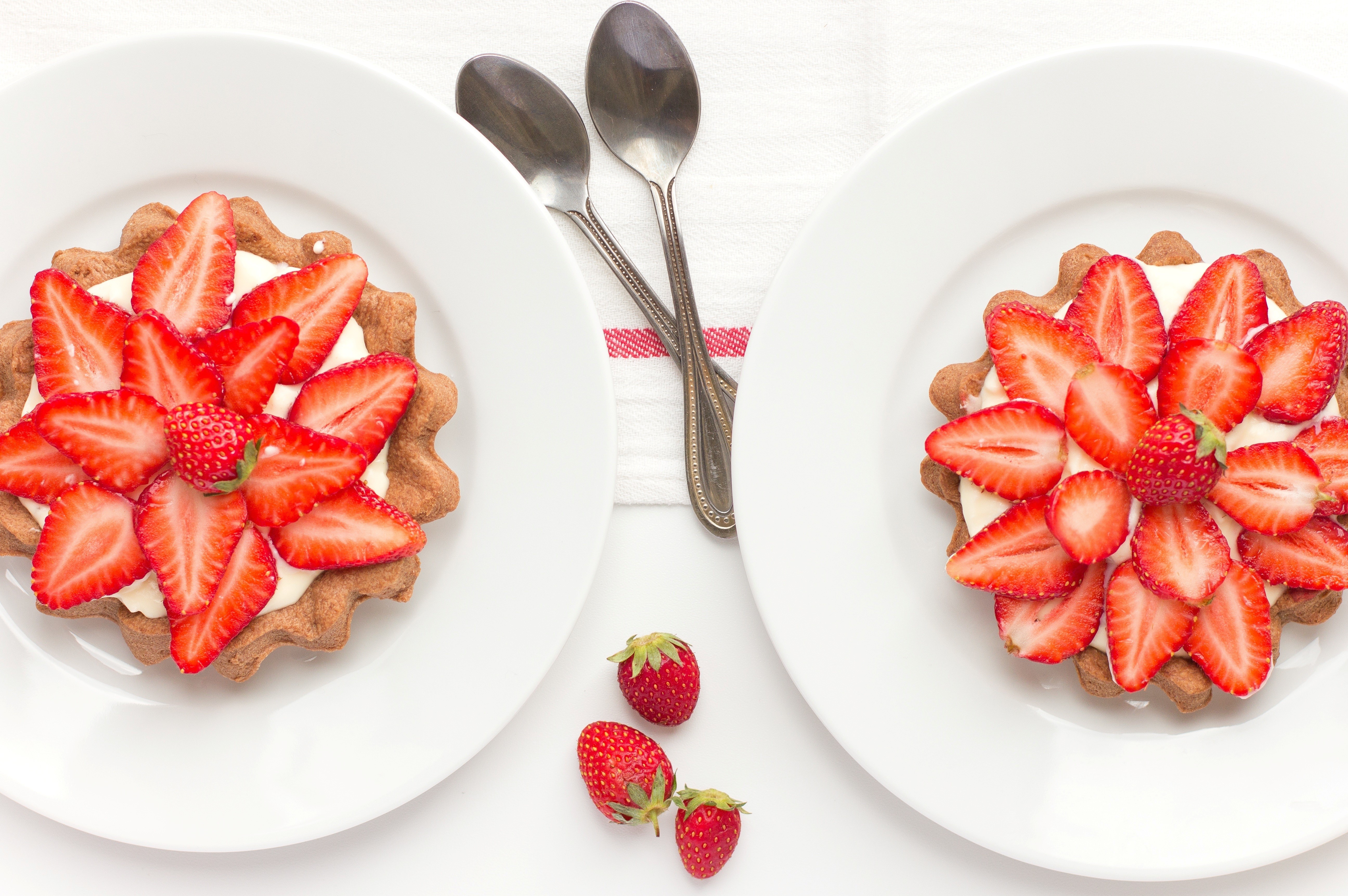 Two strawberry tarts on white plates with spoons HD Wallpaper
