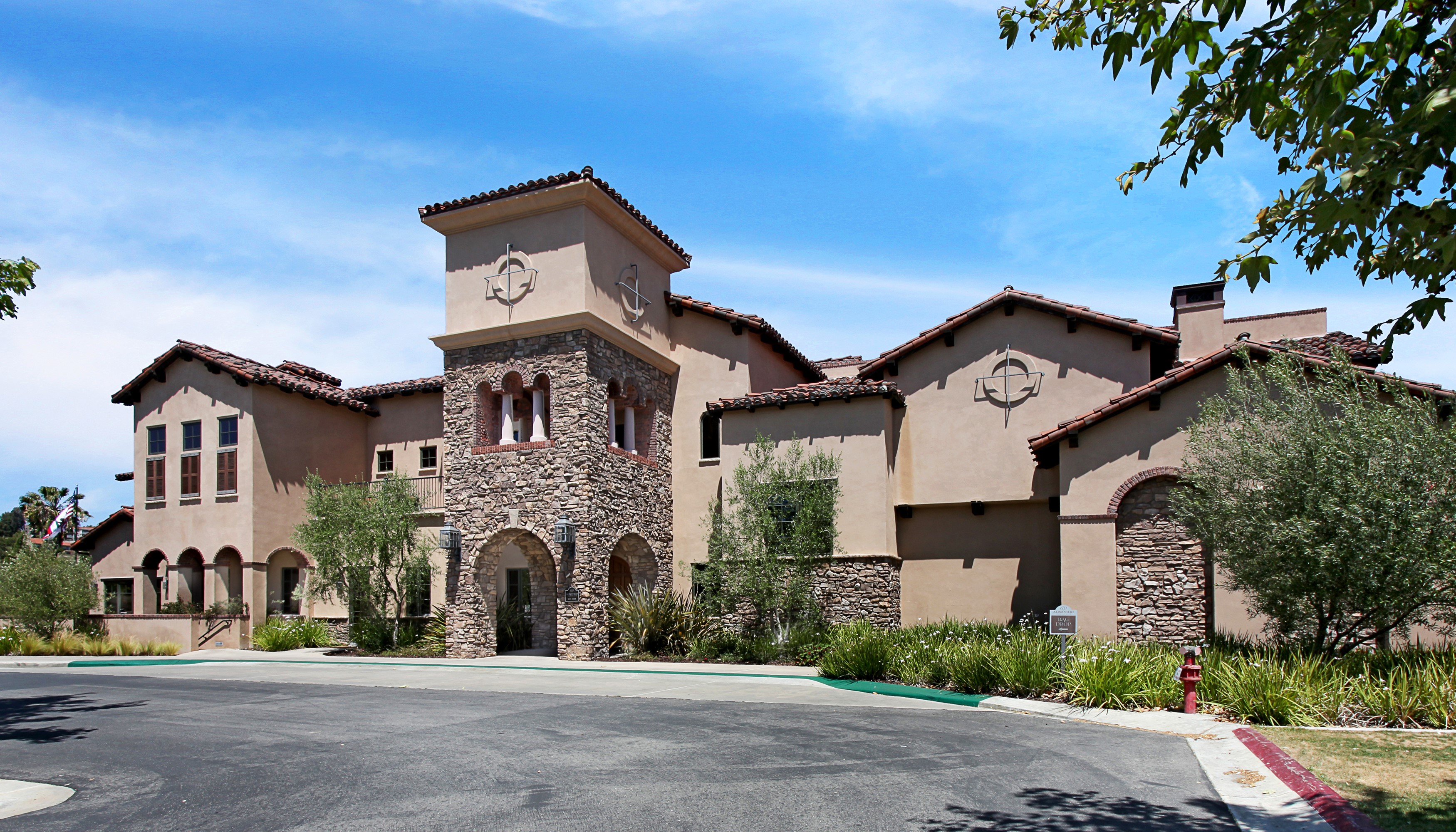 Mediterranean-style building with stone accents and trees HD Wallpaper