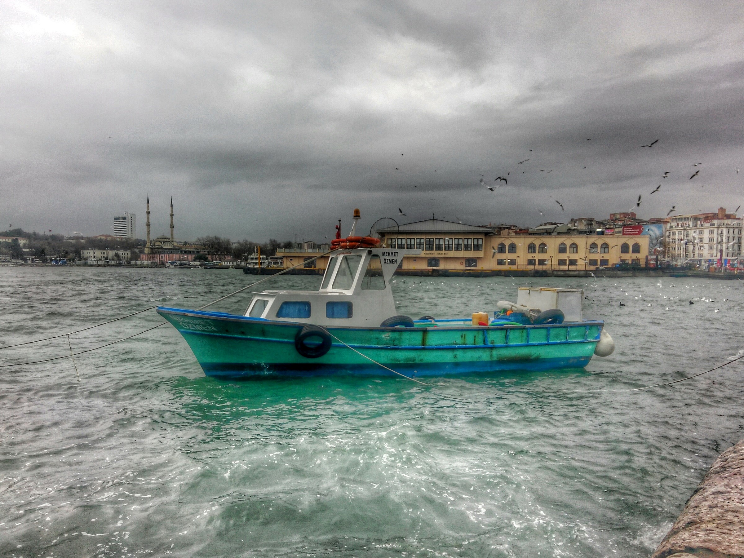 Motorboat on a river with a city skyline and mosque HD Wallpaper