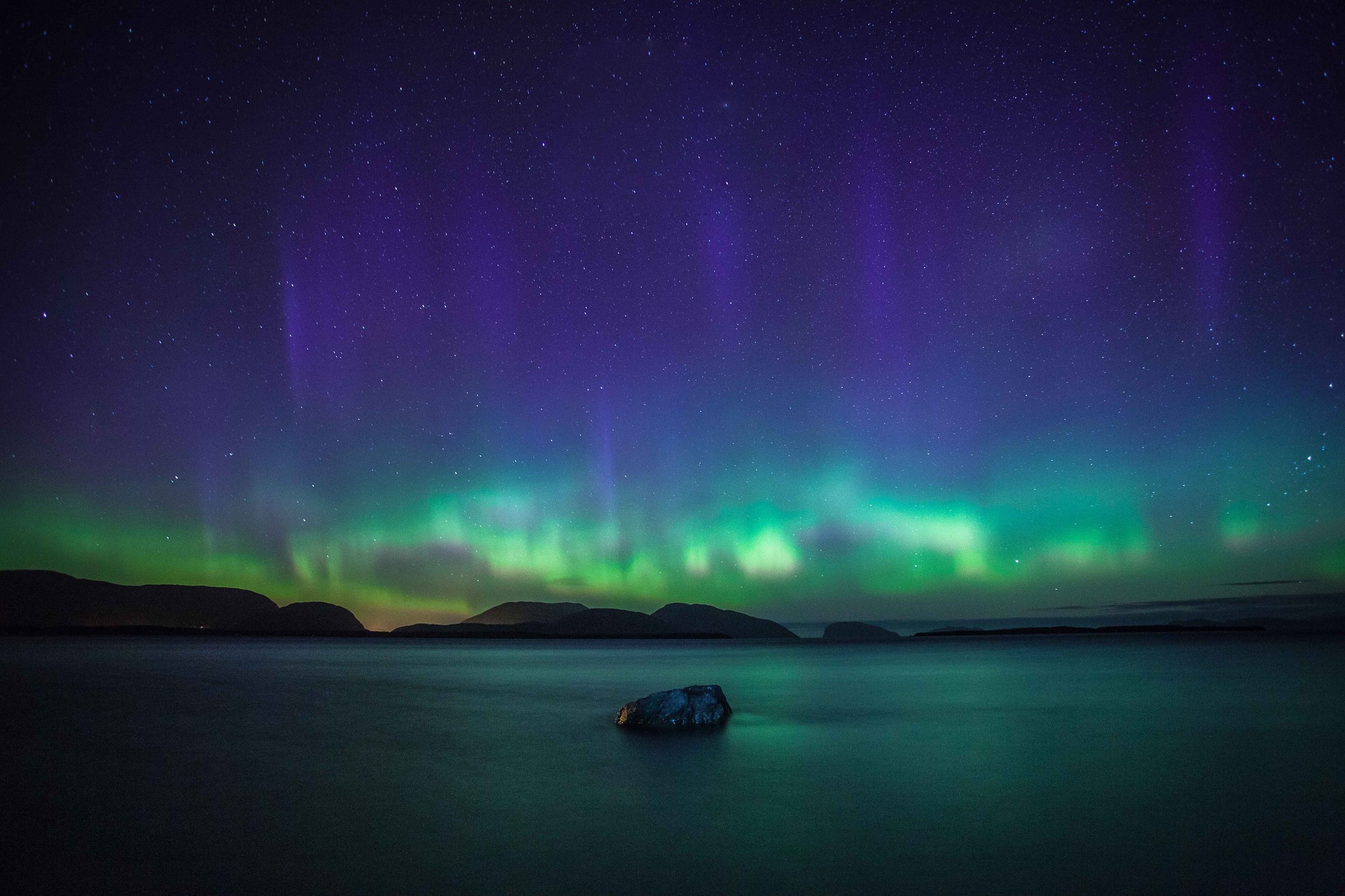 Aurora Borealis over a calm body of water with mountains HD Wallpaper