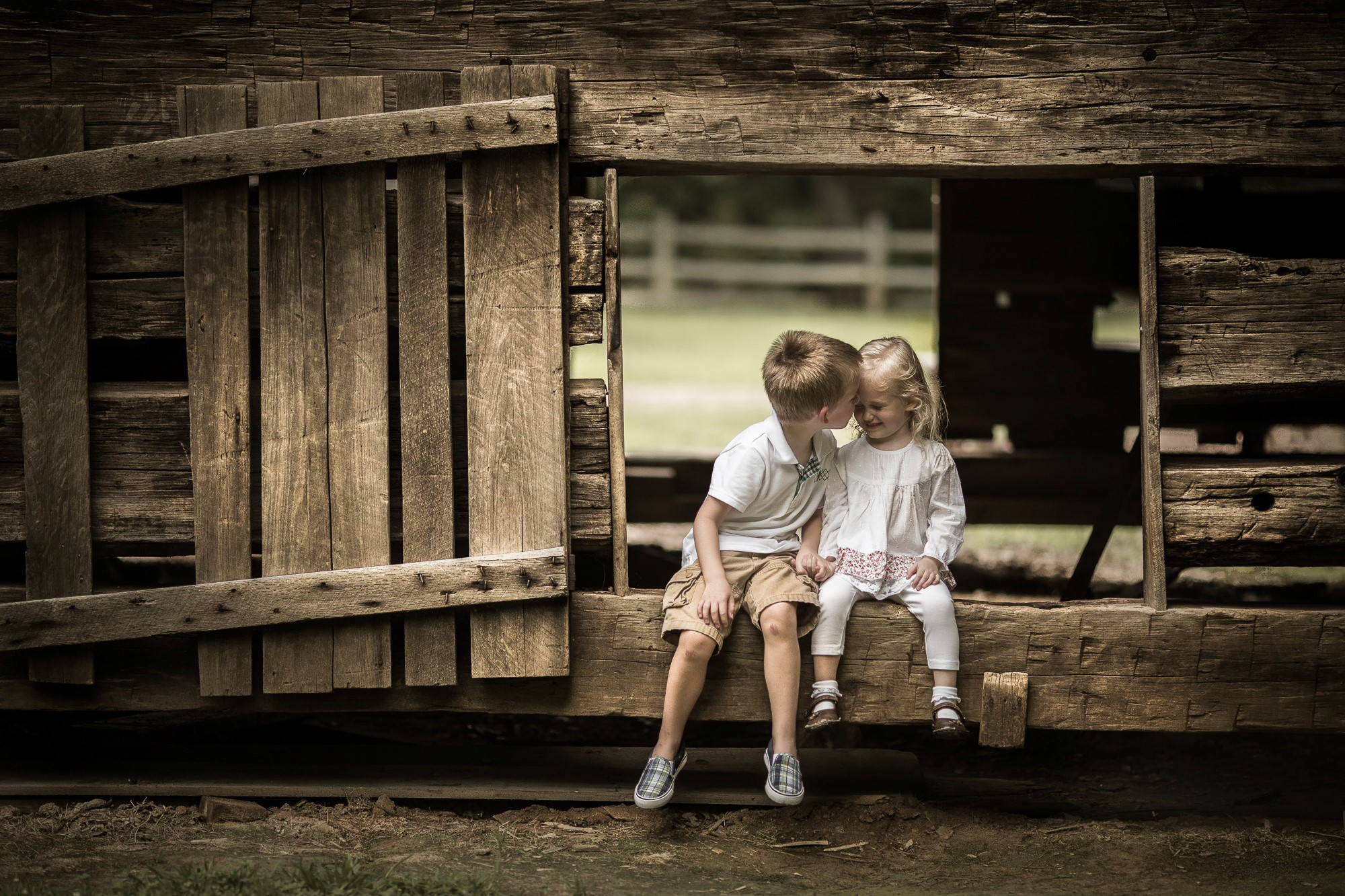 Brother and sister sitting on wooden structure HD Wallpaper