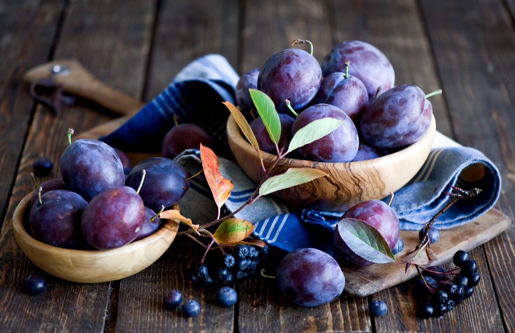 Plums and aronia berries on wooden table HD Wallpaper