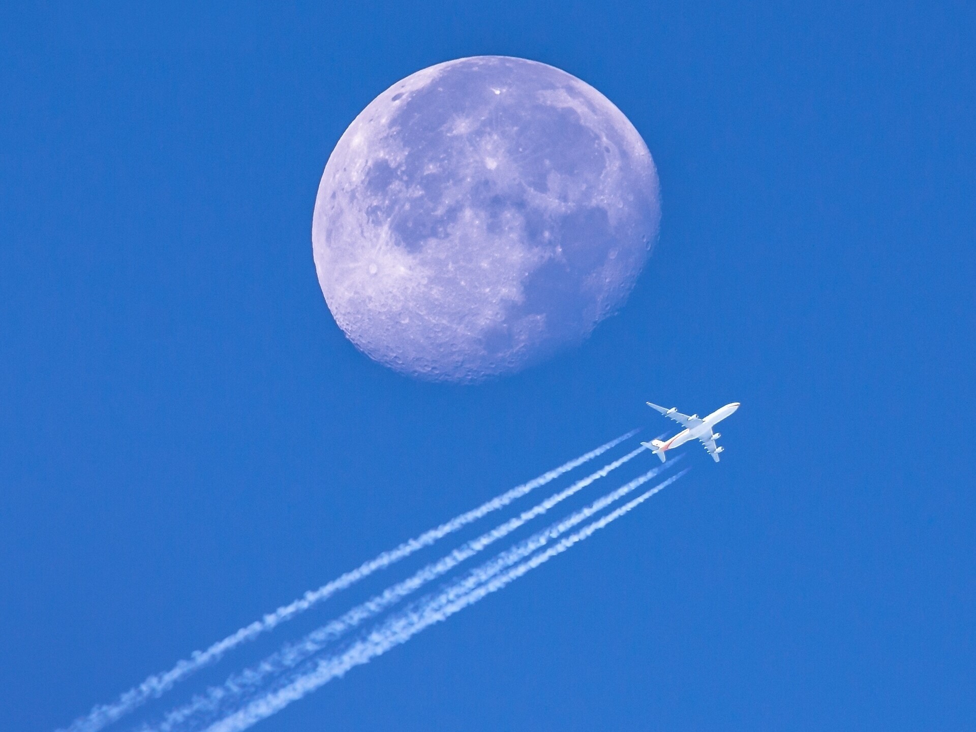 Airplane flying past the Moon in a blue sky HD Wallpaper