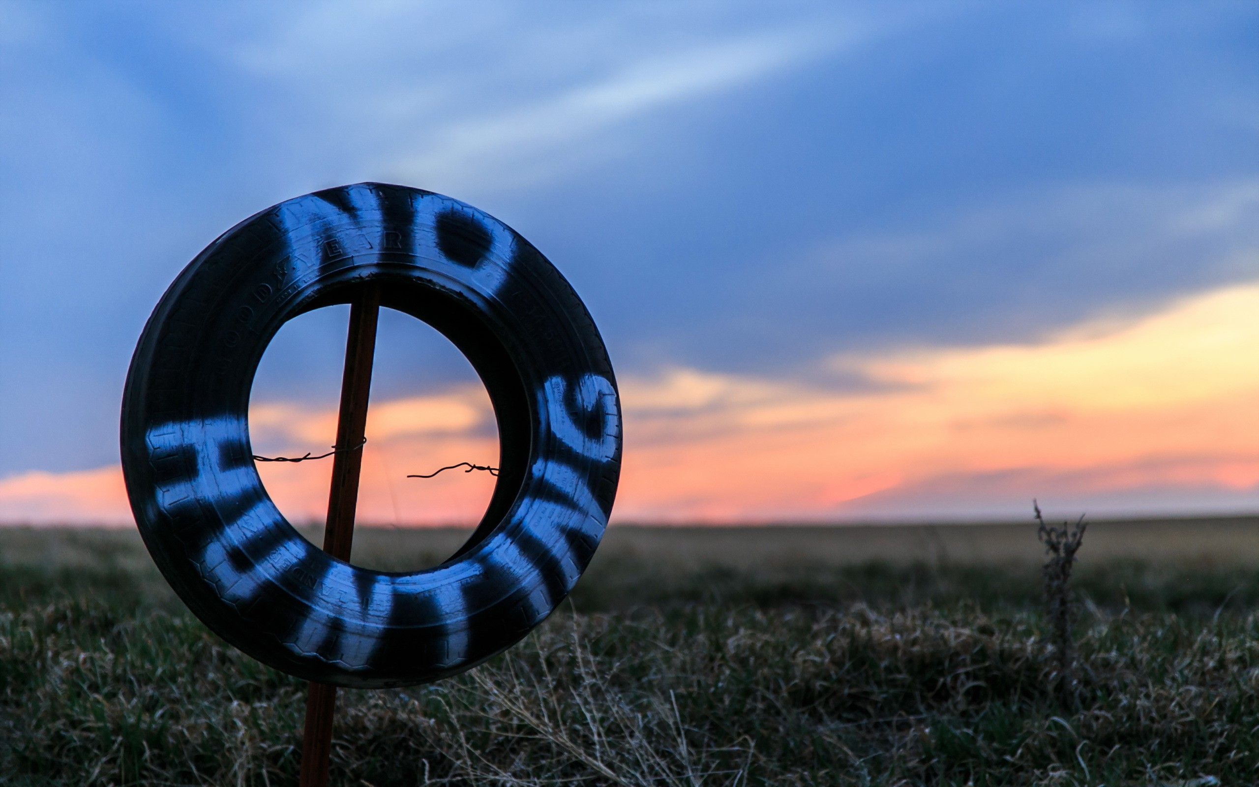 Tire with "NO HUNTING" spray painted on it at sunset HD Wallpaper