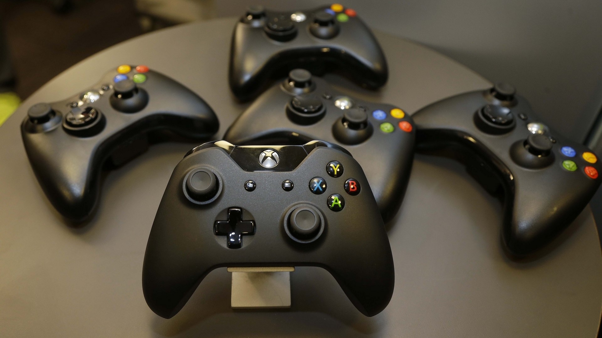Multiple black Xbox controllers on a table HD Wallpaper