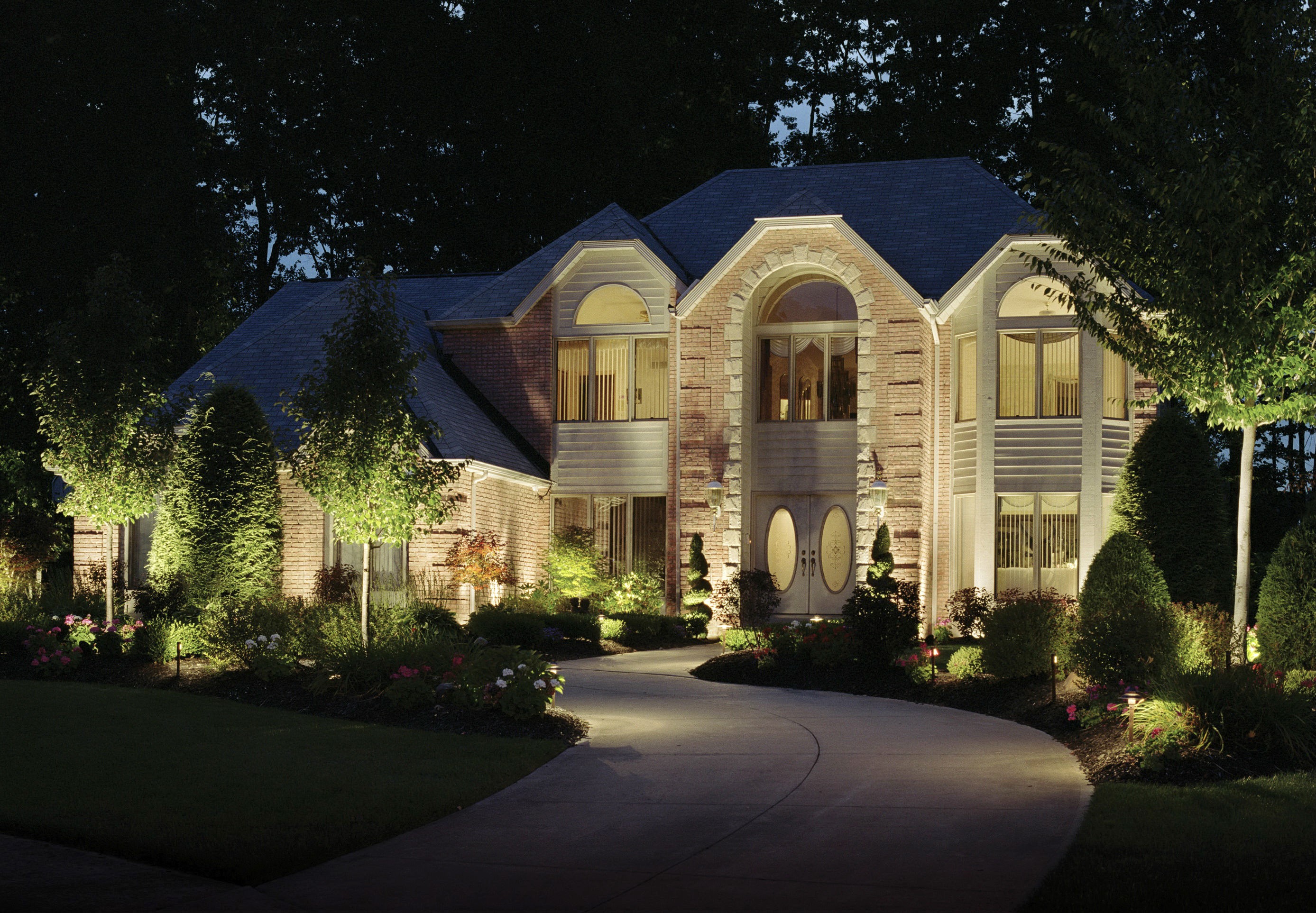 Brick house with illuminated landscaping at night HD Wallpaper