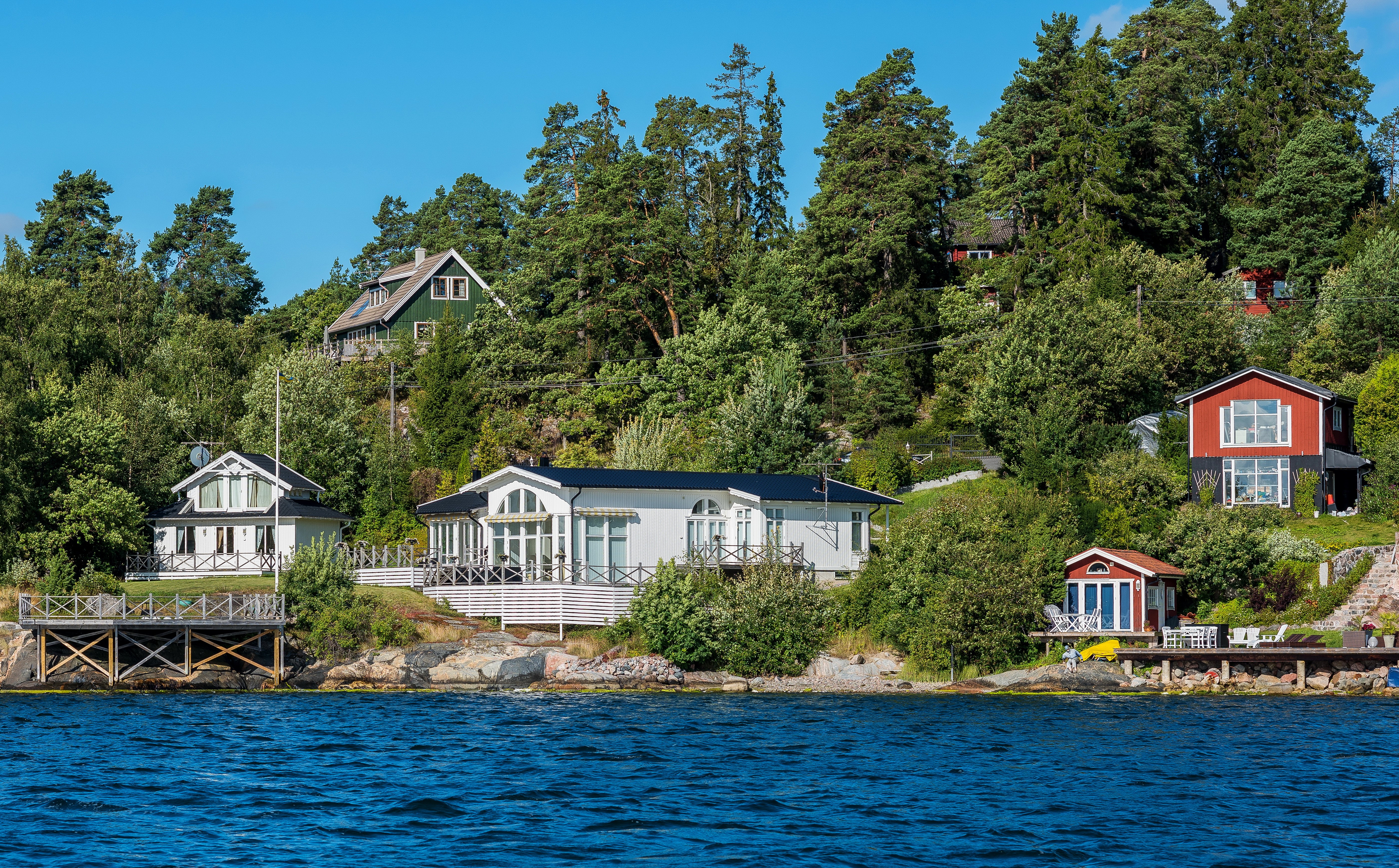 Houses on a wooded hillside by the water in Sweden HD Wallpaper