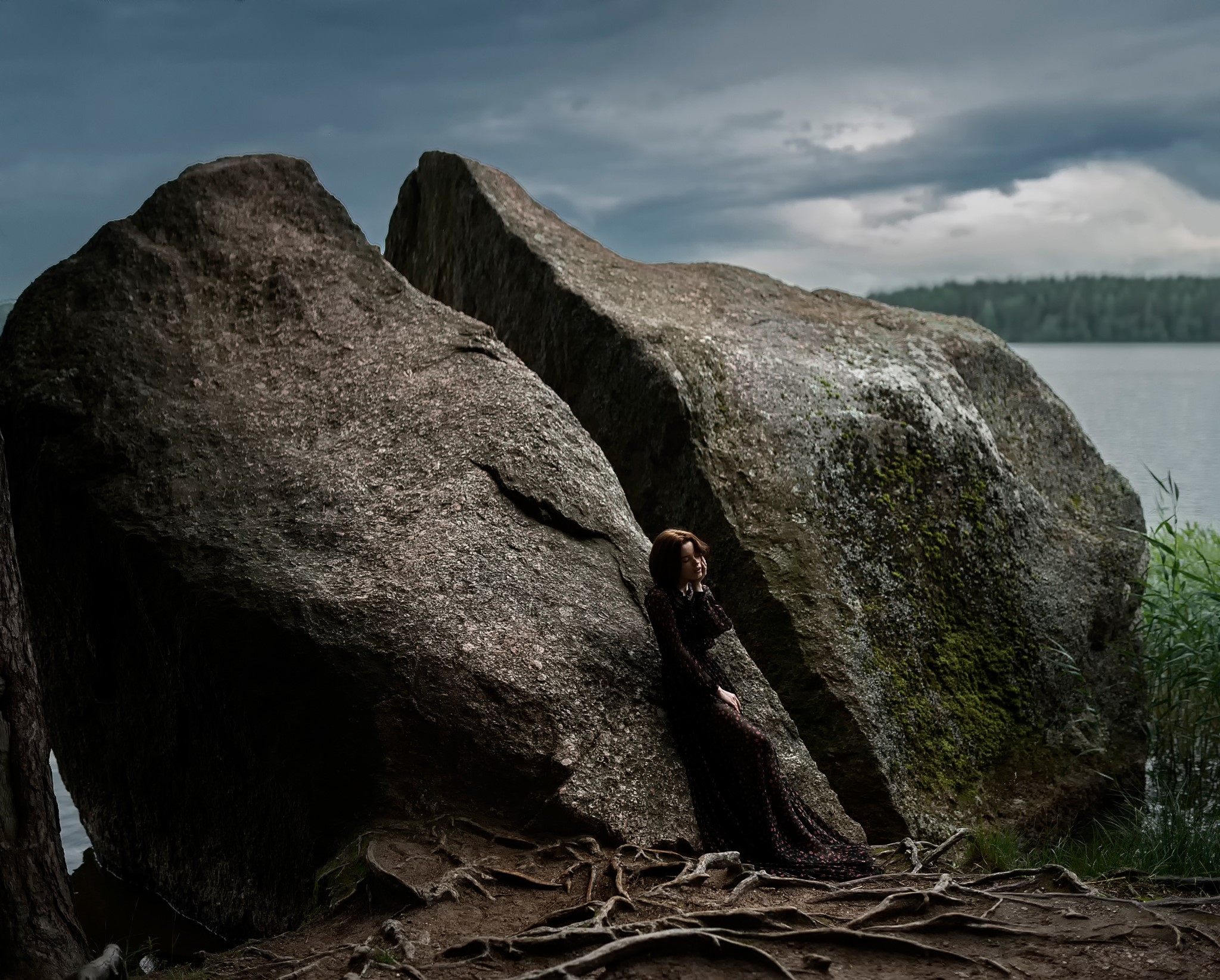 Woman leaning on large rocks by a lake HD Wallpaper