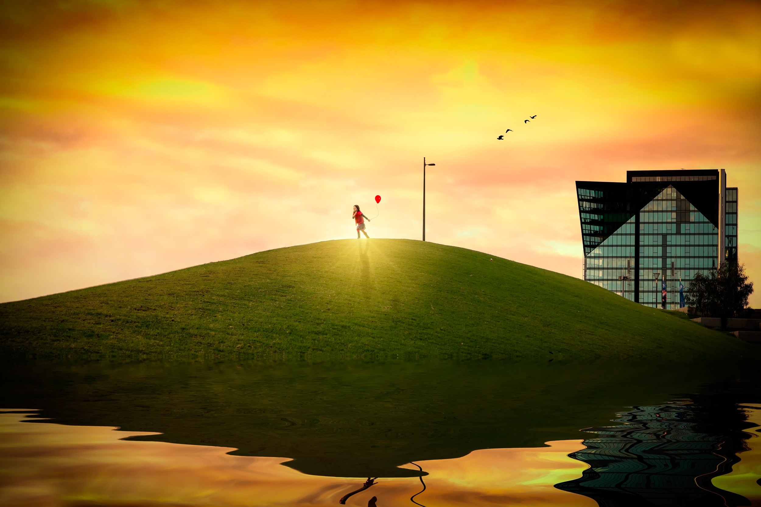 Girl with red balloon on grassy hill with building reflection HD Wallpaper