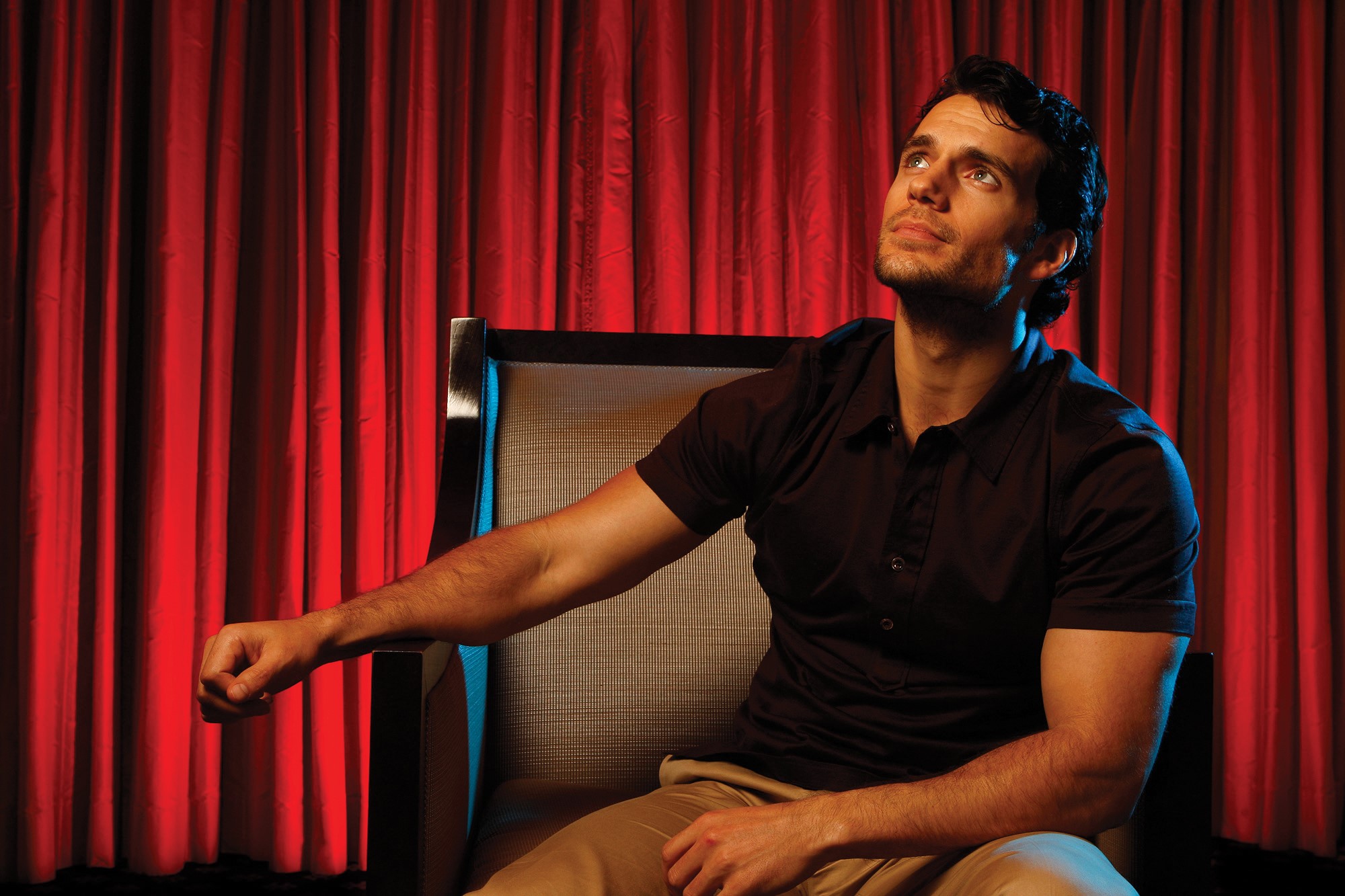 Henry Cavill sitting in front of red curtains HD Wallpaper