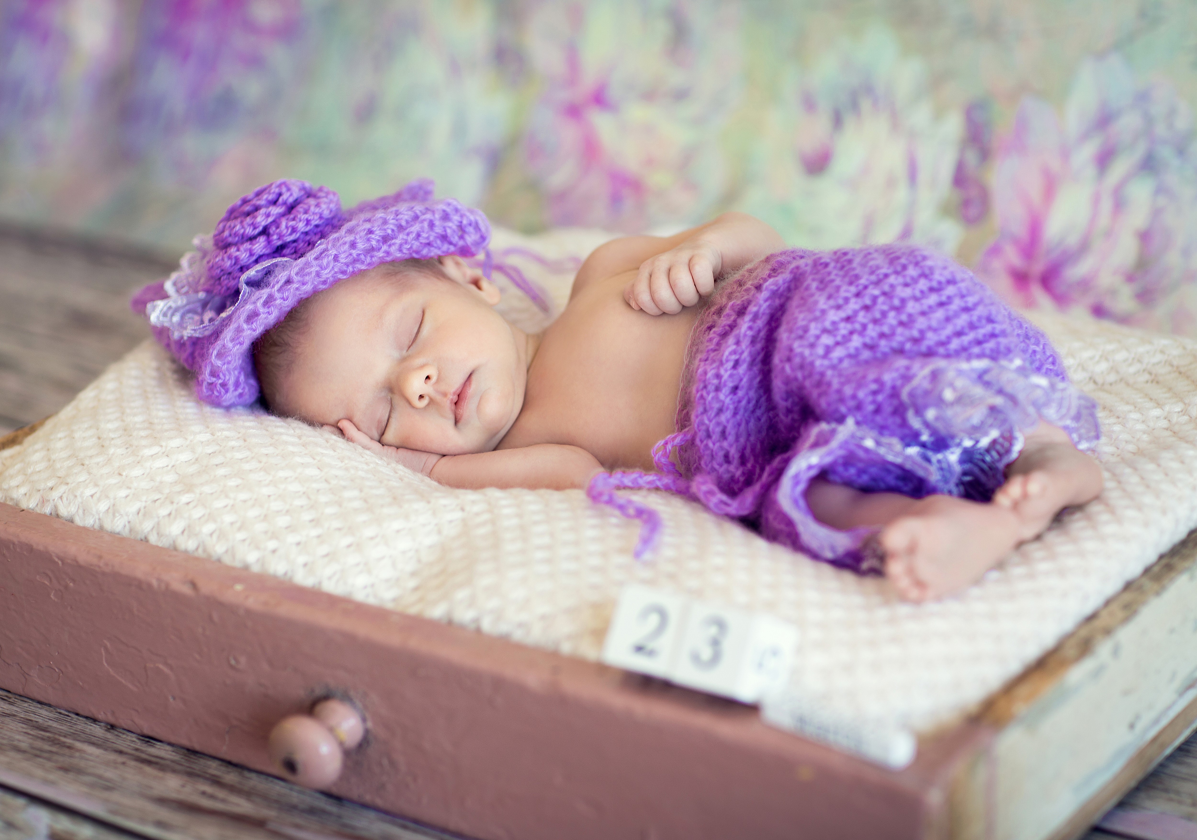Newborn baby sleeping in a drawer with purple hat HD Wallpaper
