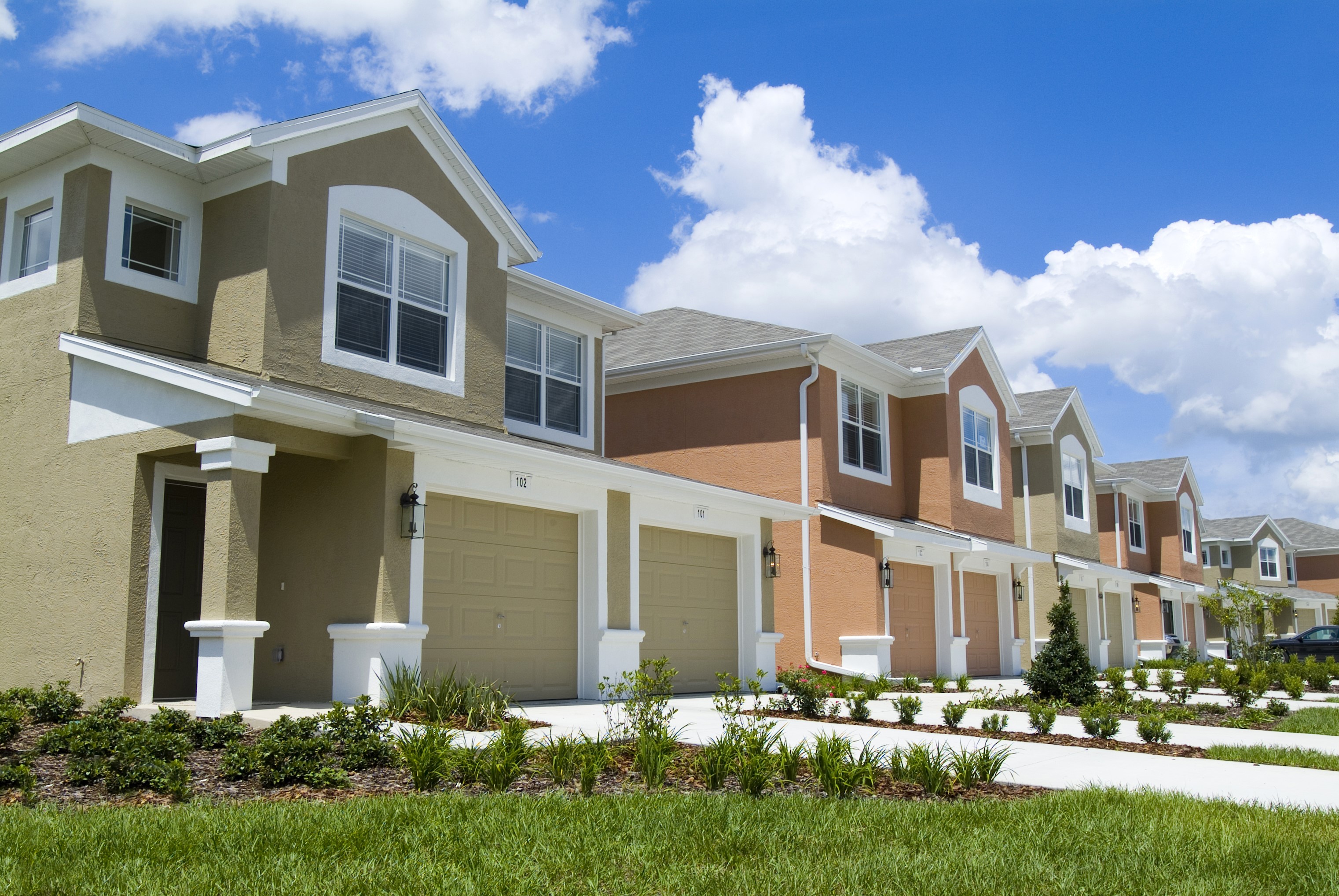 Row of townhouses with garages and blue sky HD Wallpaper