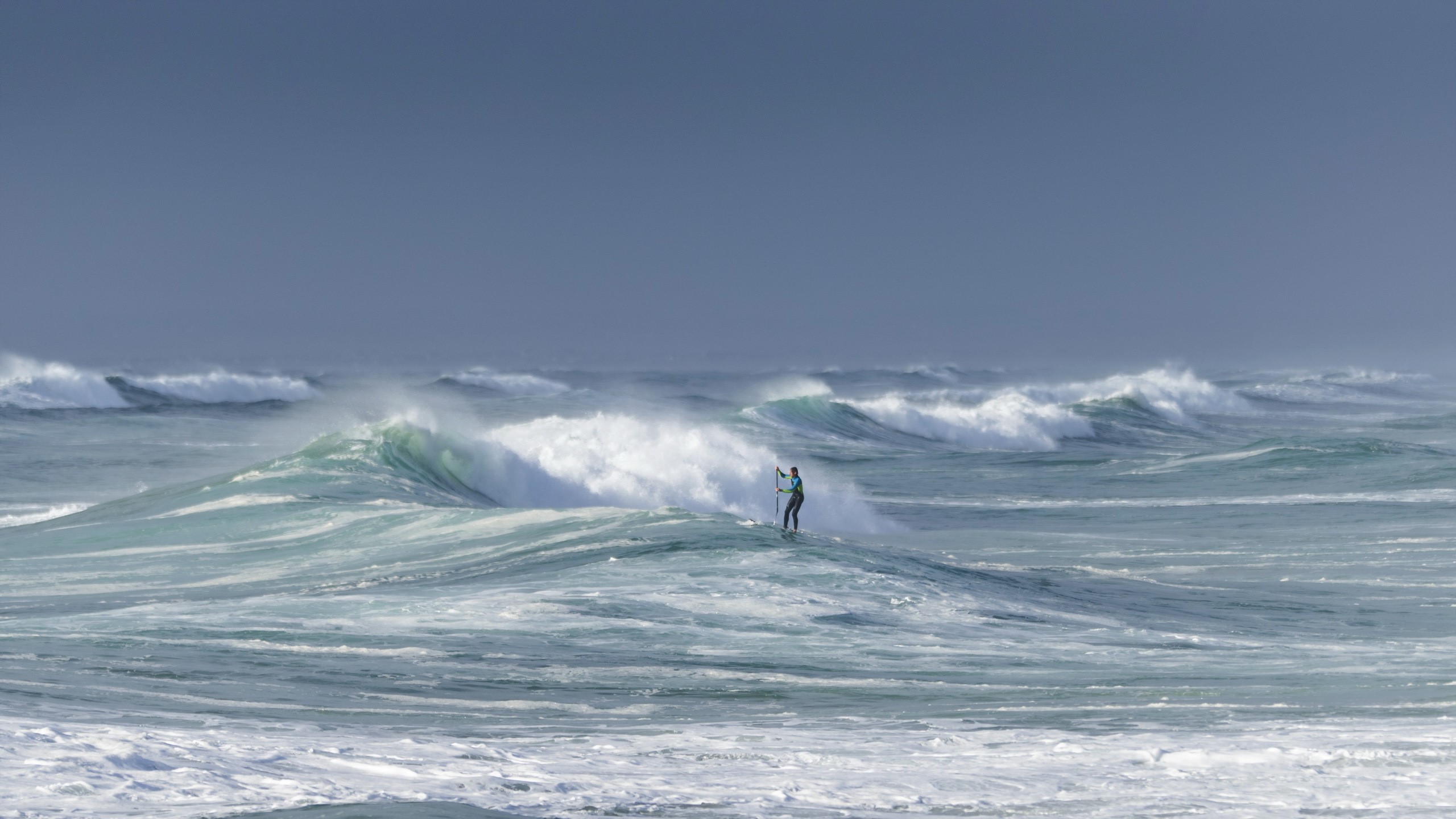 Person paddleboarding on large ocean waves HD Wallpaper