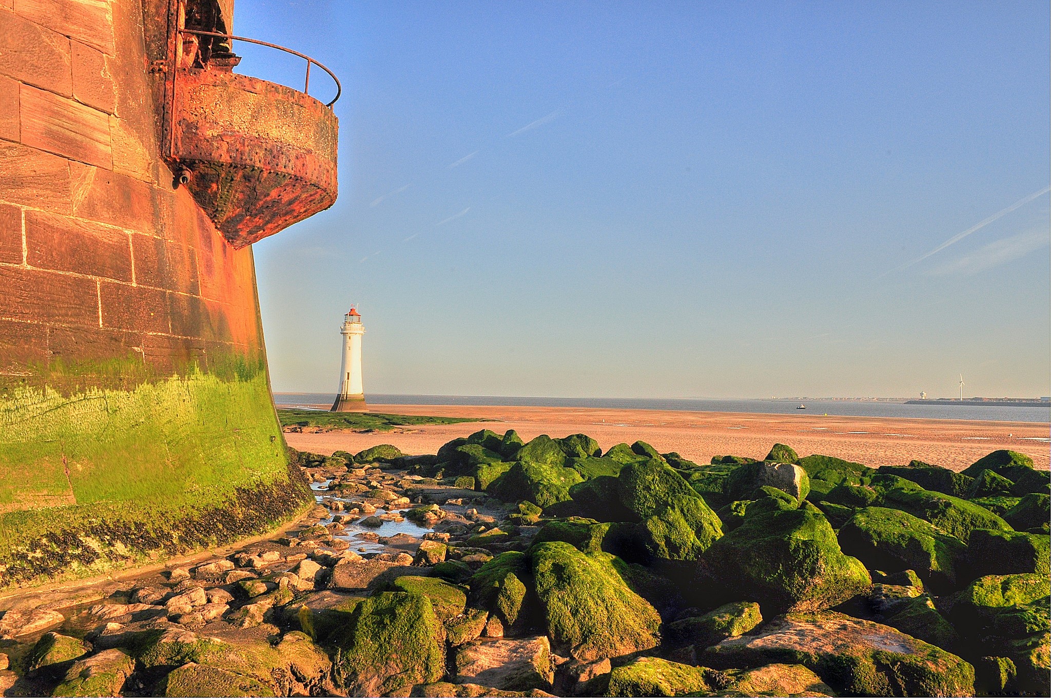 Lighthouse on a rocky coast with mossy stones HD Wallpaper