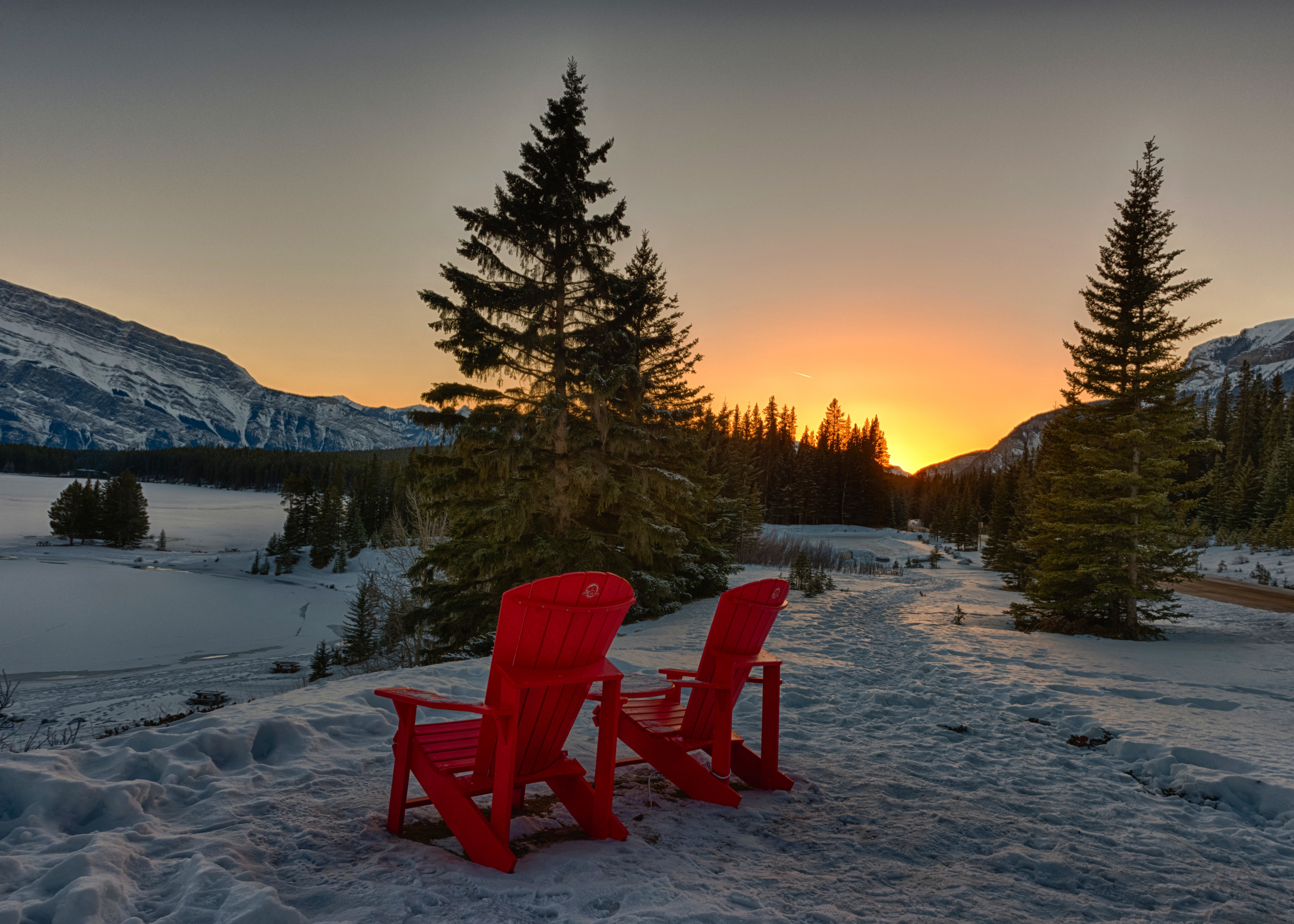 Winter sunset with red chairs overlooking snowy landscape HD Wallpaper