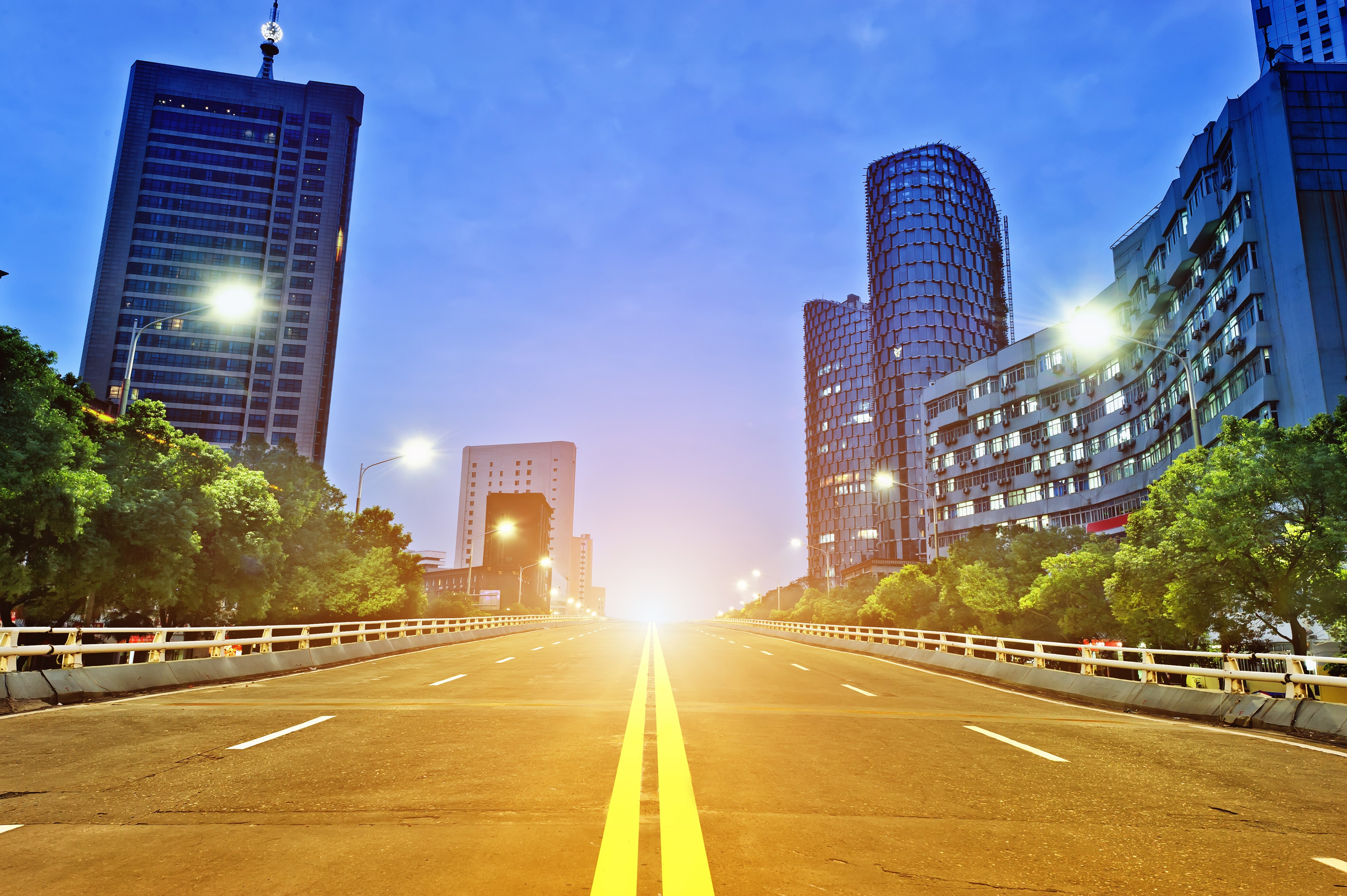Road leading to modern city buildings at dusk HD Wallpaper