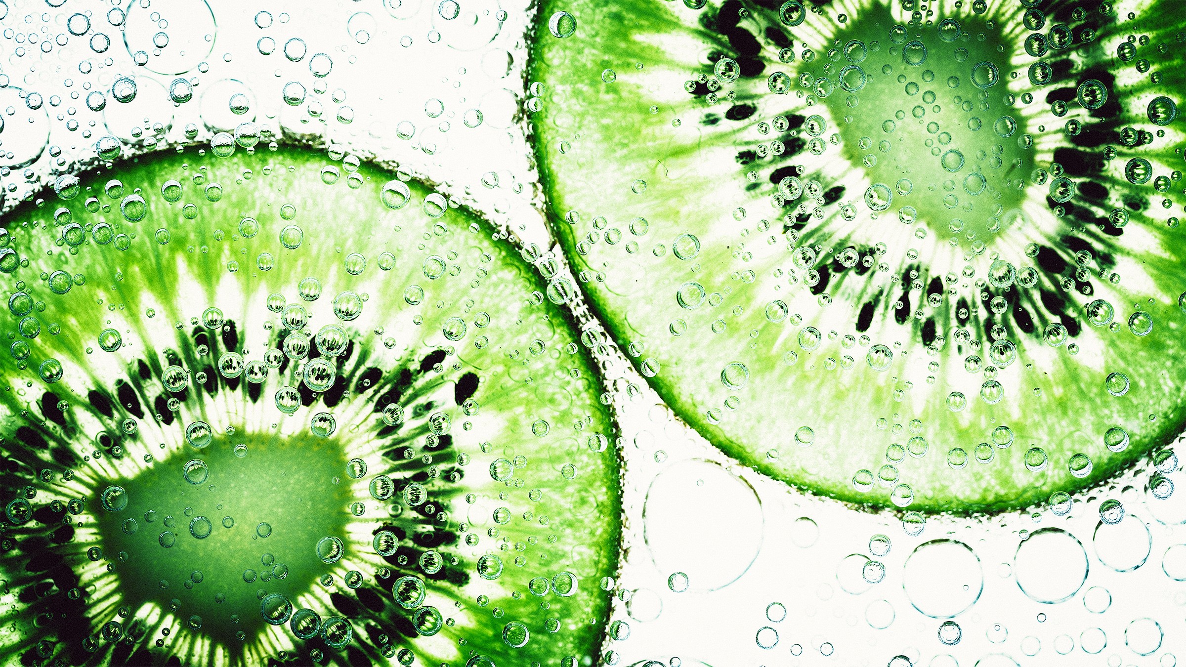 Close-up of kiwi slices in water with bubbles HD Wallpaper