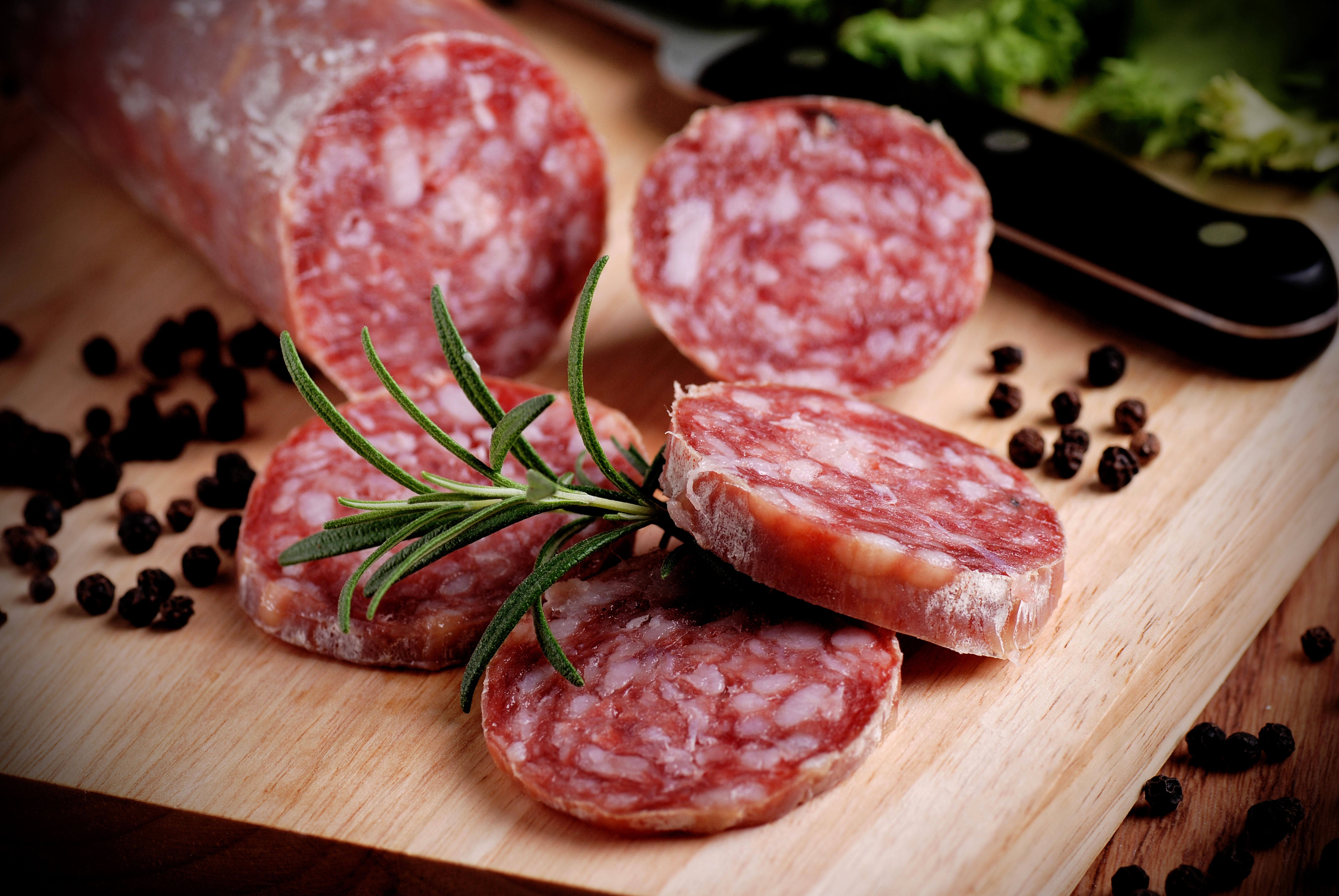 Sausage slices with rosemary and peppercorns on a cutting board HD Wallpaper