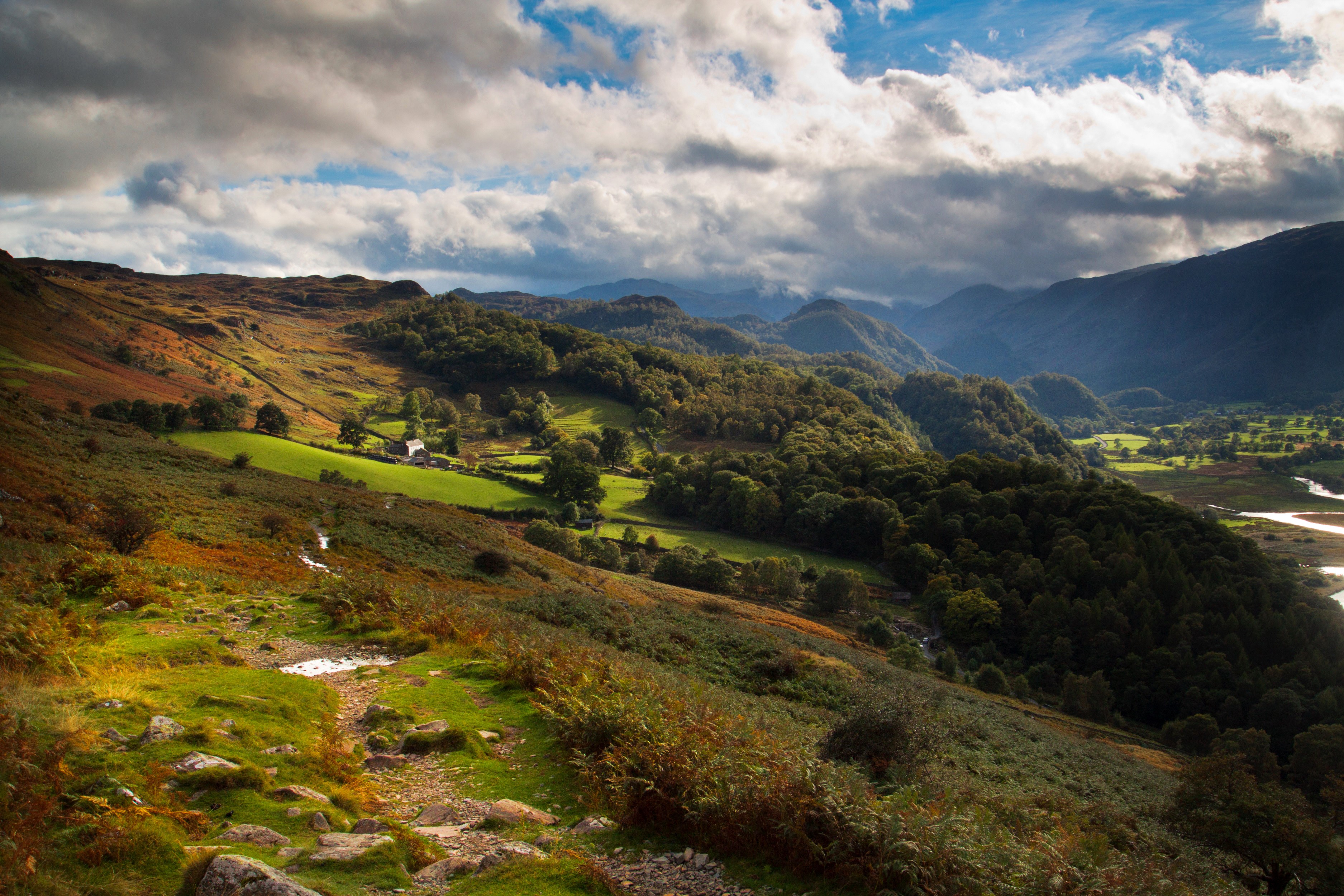 Rolling hills and mountains with a valley and river HD Wallpaper