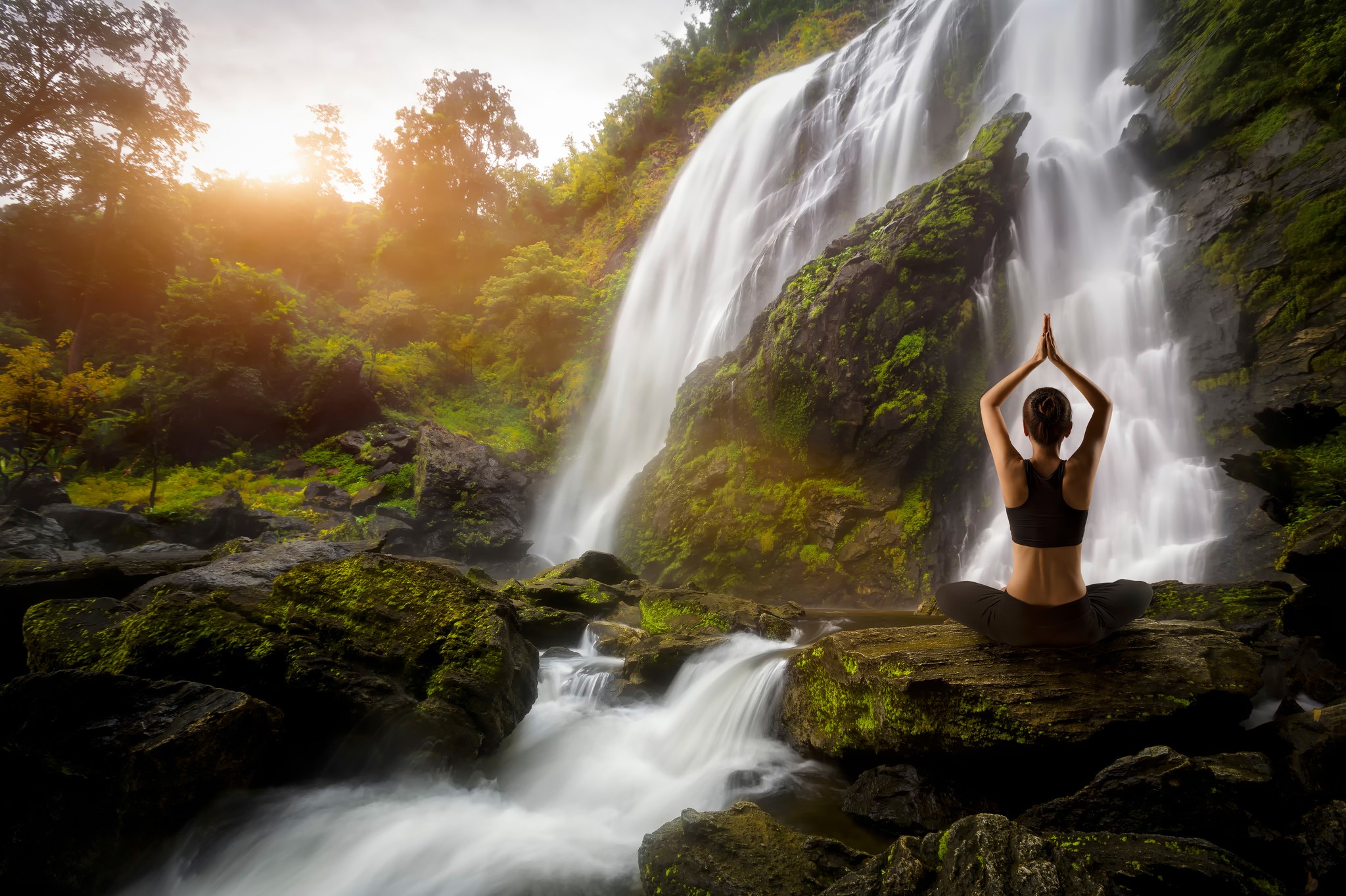 Woman meditating by a waterfall HD Wallpaper