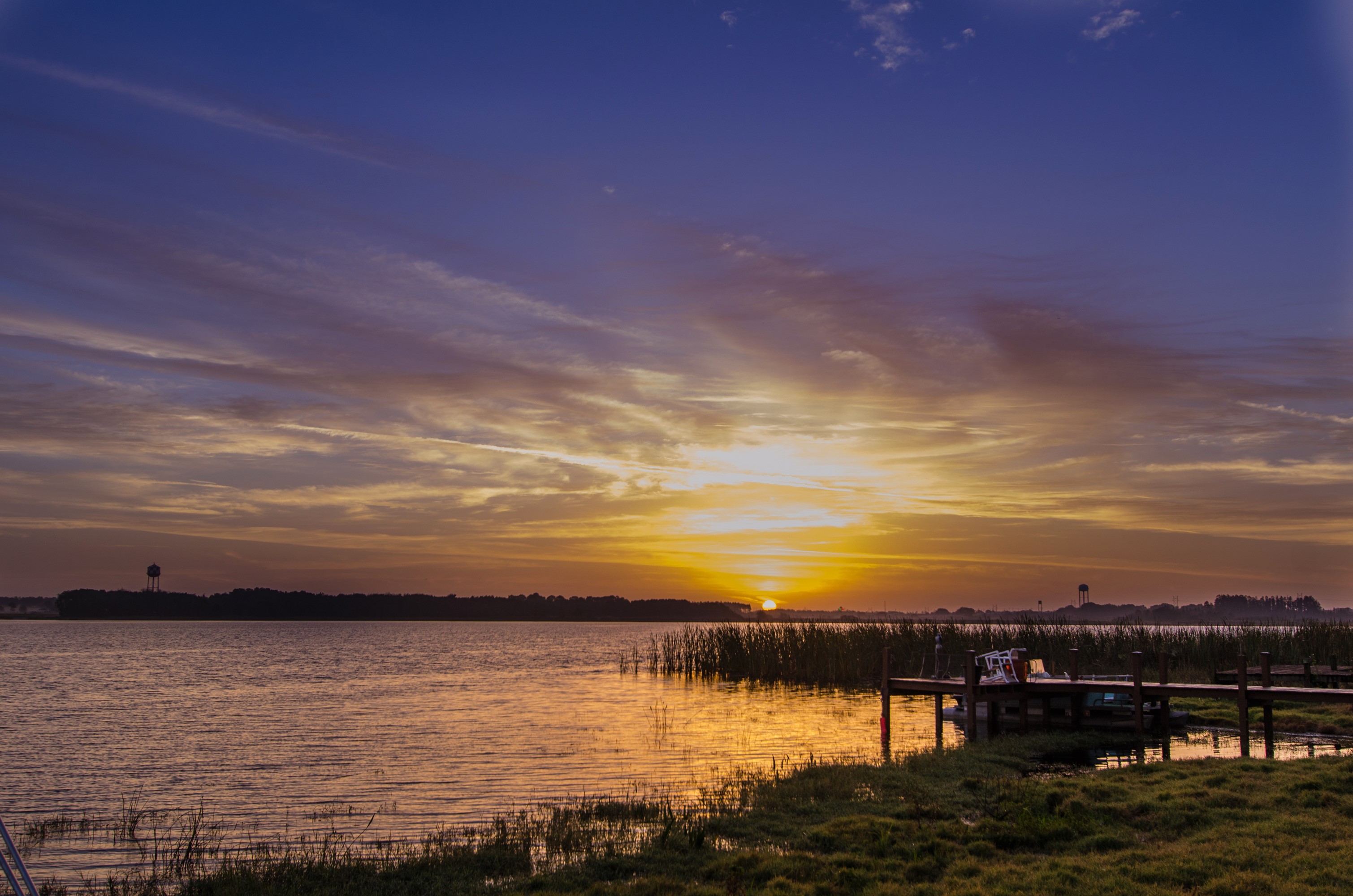 Sunset over a lake with a dock and reeds HD Wallpaper
