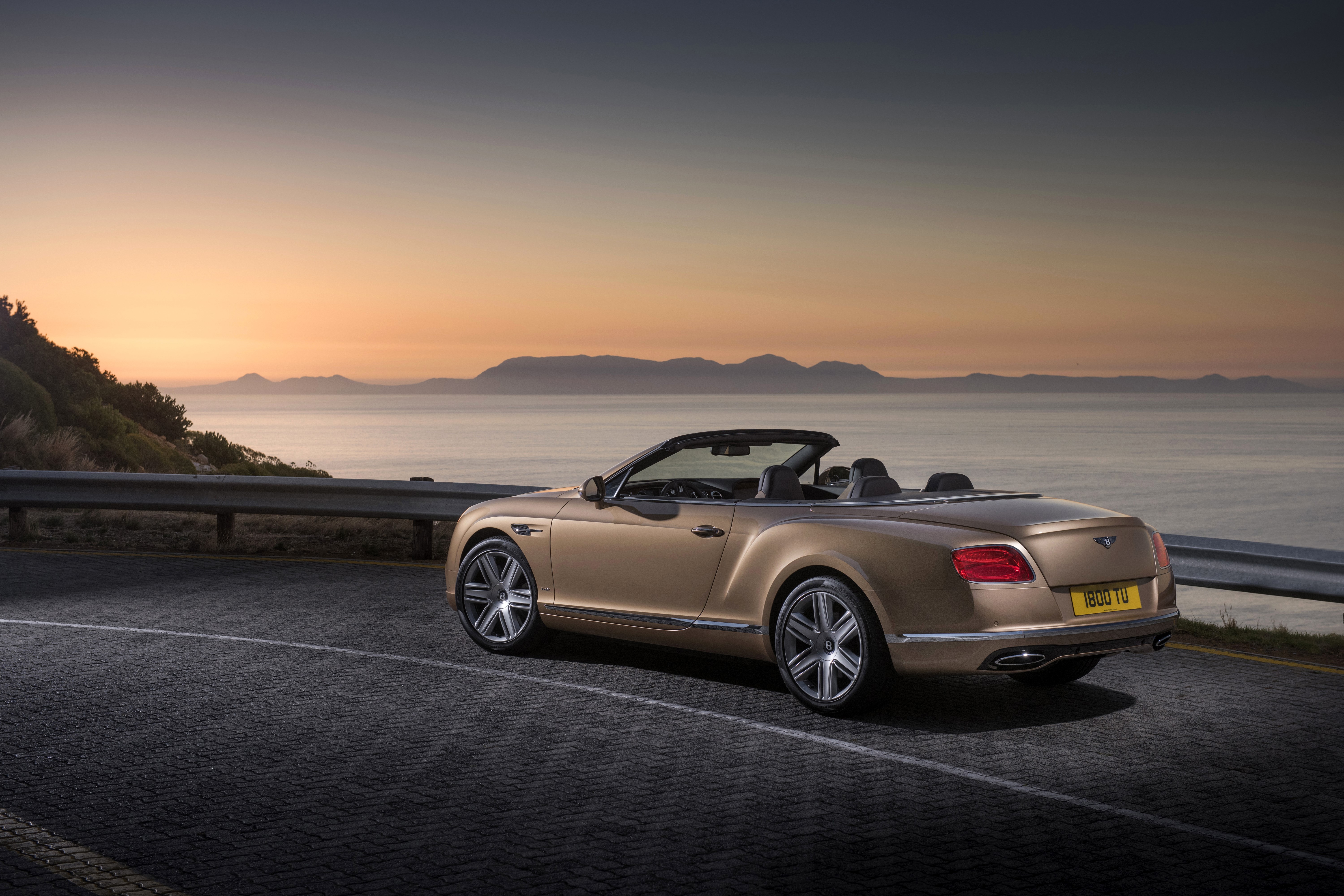 Bentley Continental GTC convertible on a coastal road at sunset HD Wallpaper