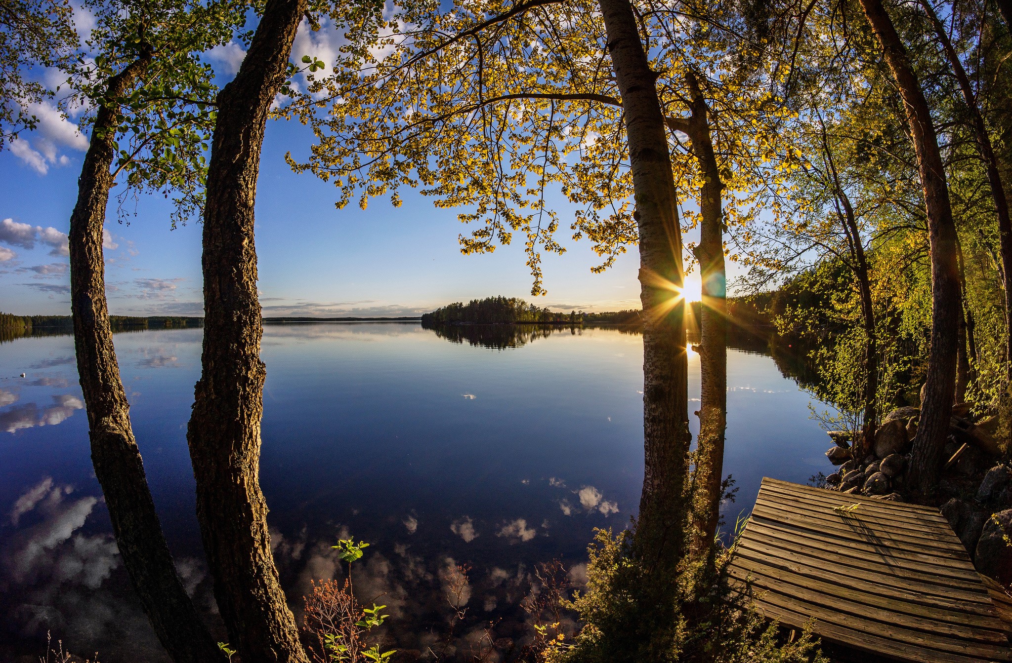 Sunset over a calm lake with trees and a wooden pier HD Wallpaper
