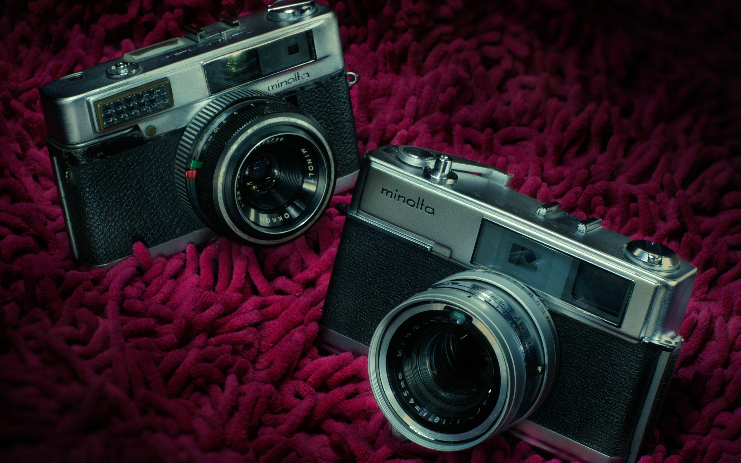 Two retro Minolta cameras on a textured surface HD Wallpaper