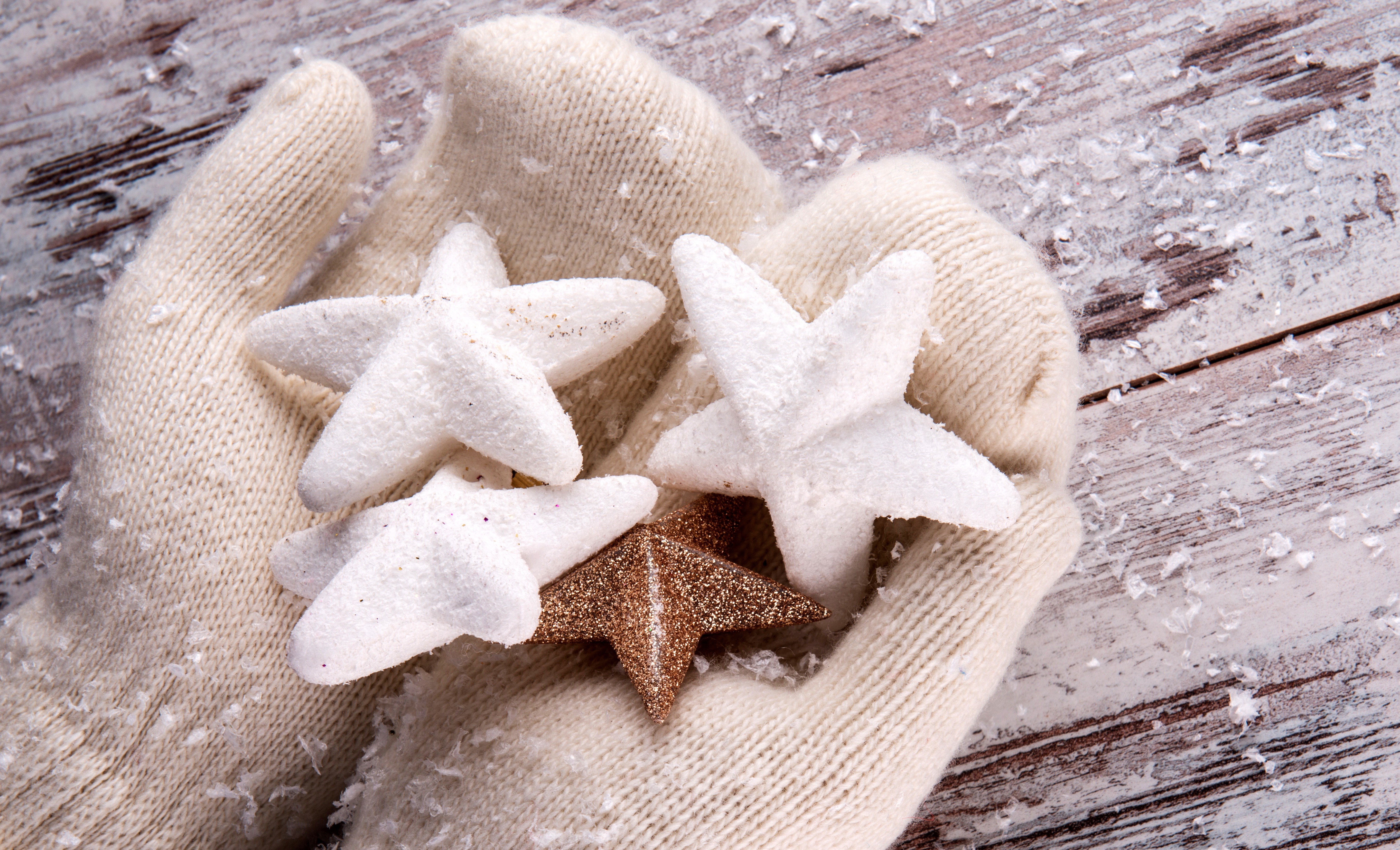 Hands in mittens holding star ornaments with snow HD Wallpaper