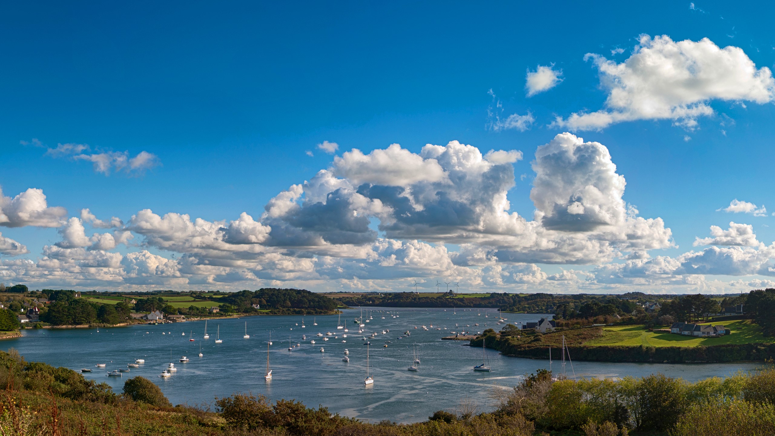 Boats on a wide river under a cloudy blue sky HD Wallpaper
