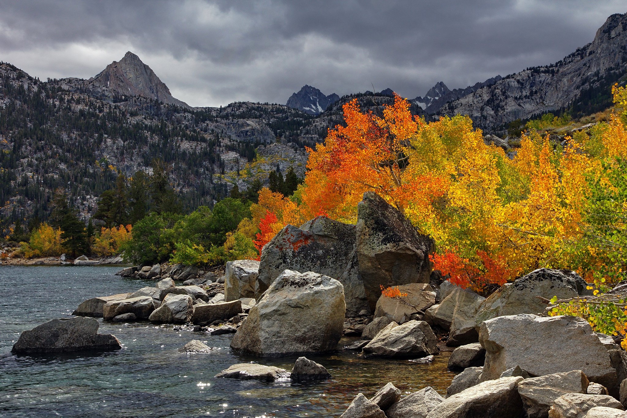 Autumn foliage by a rocky lake with mountains HD Wallpaper