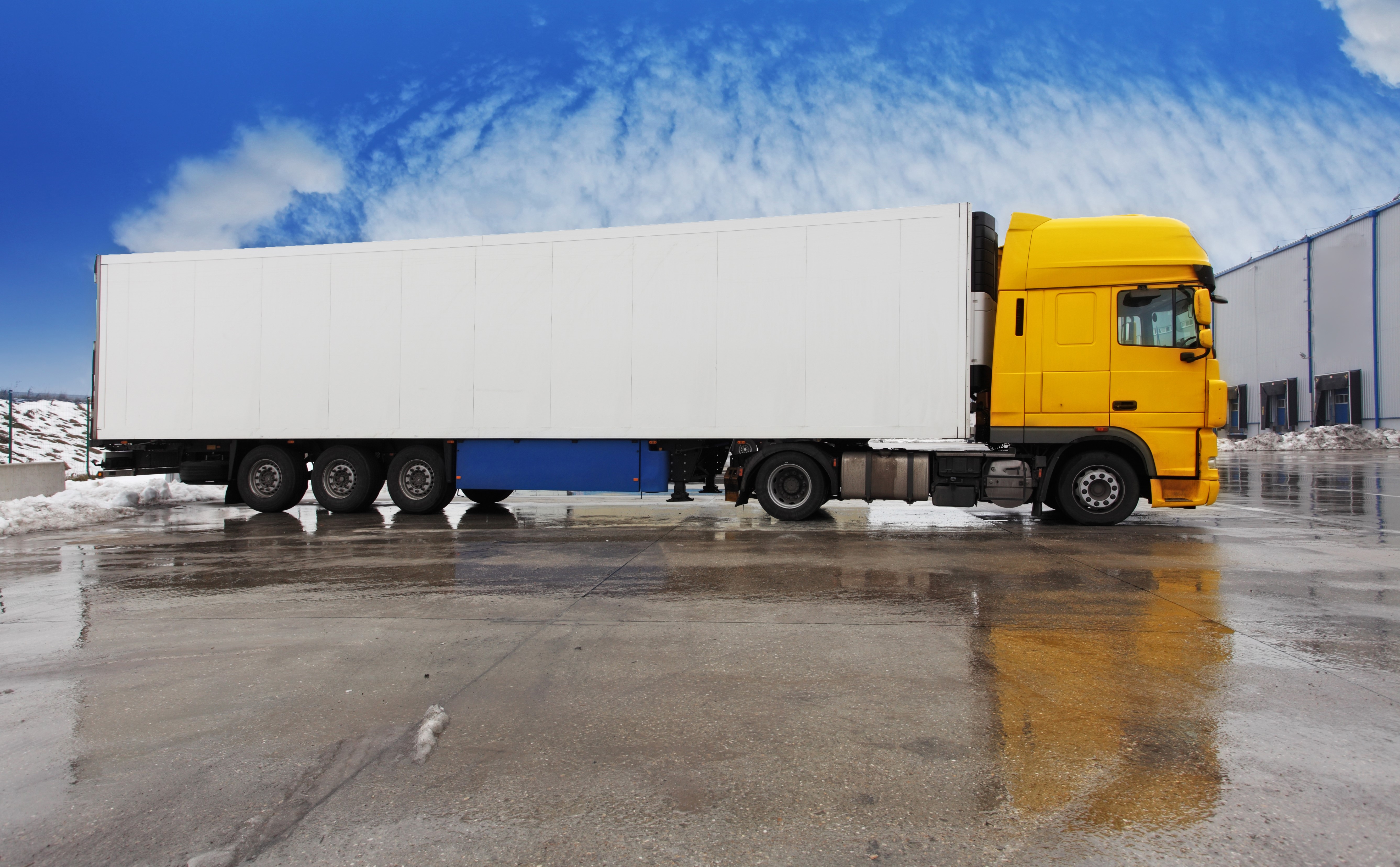 Yellow truck with white trailer on wet ground HD Wallpaper