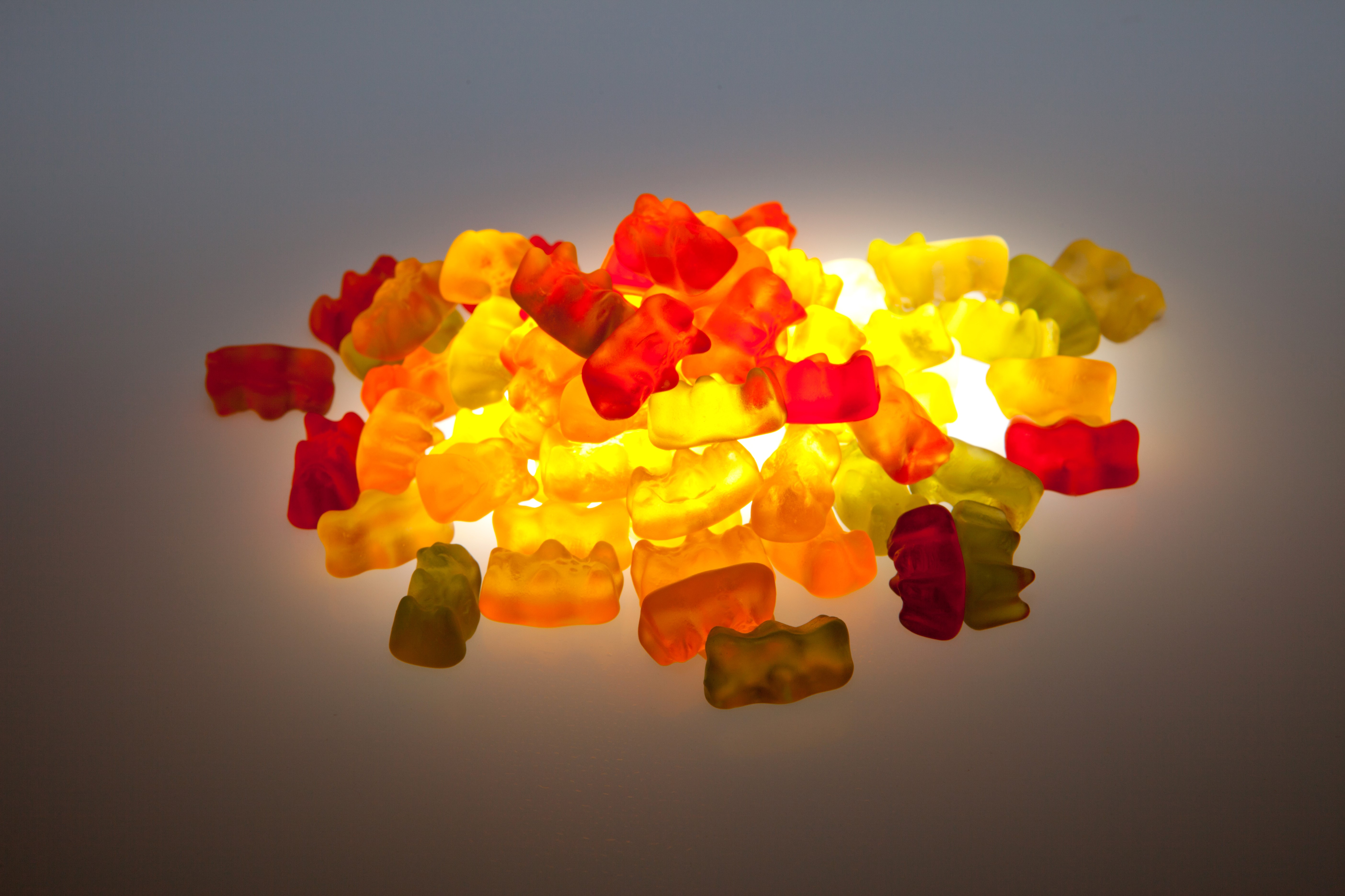 Pile of colorful gummy bears illuminated from behind HD Wallpaper