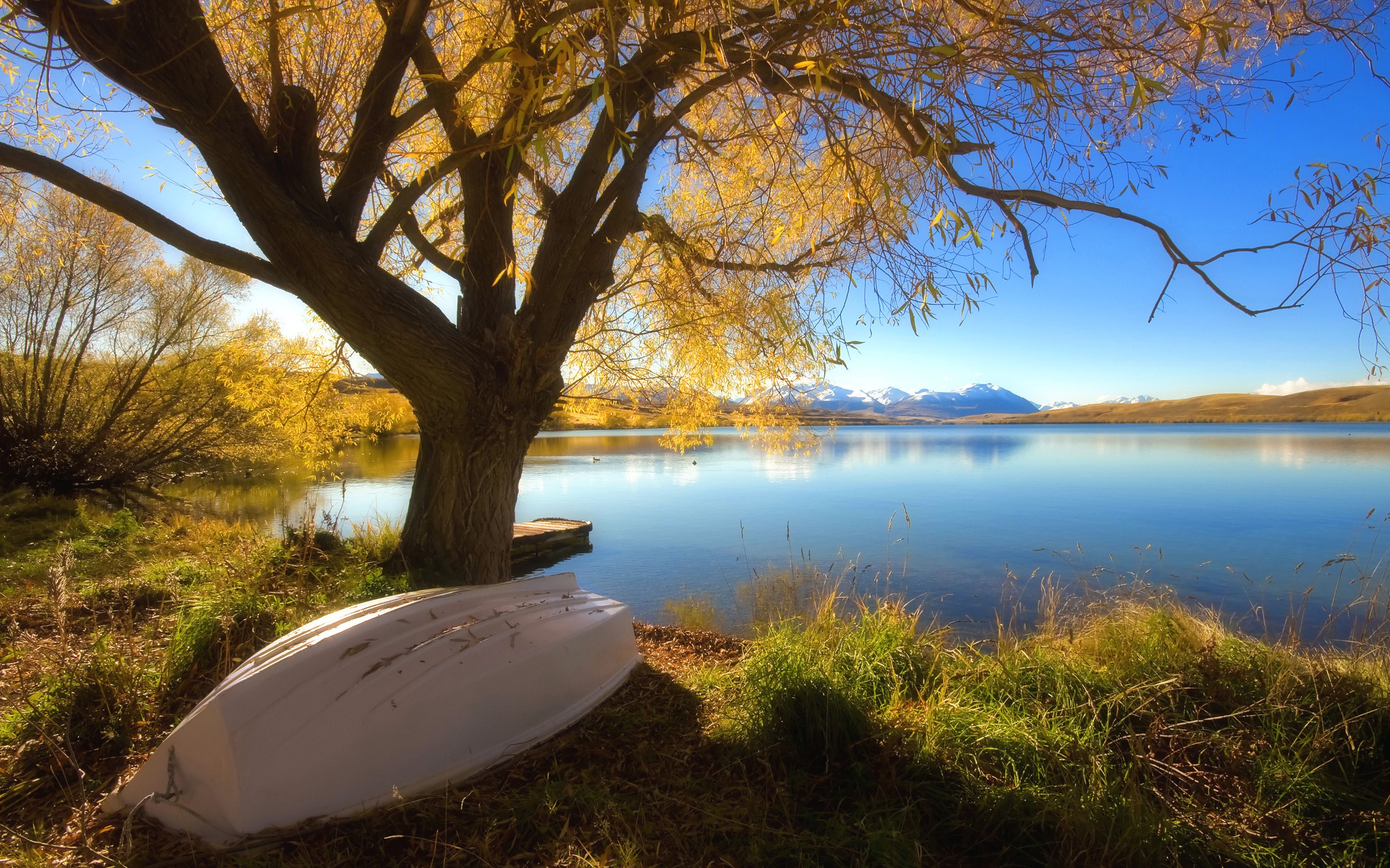 Autumn lake with a boat and snow-capped mountains HD Wallpaper