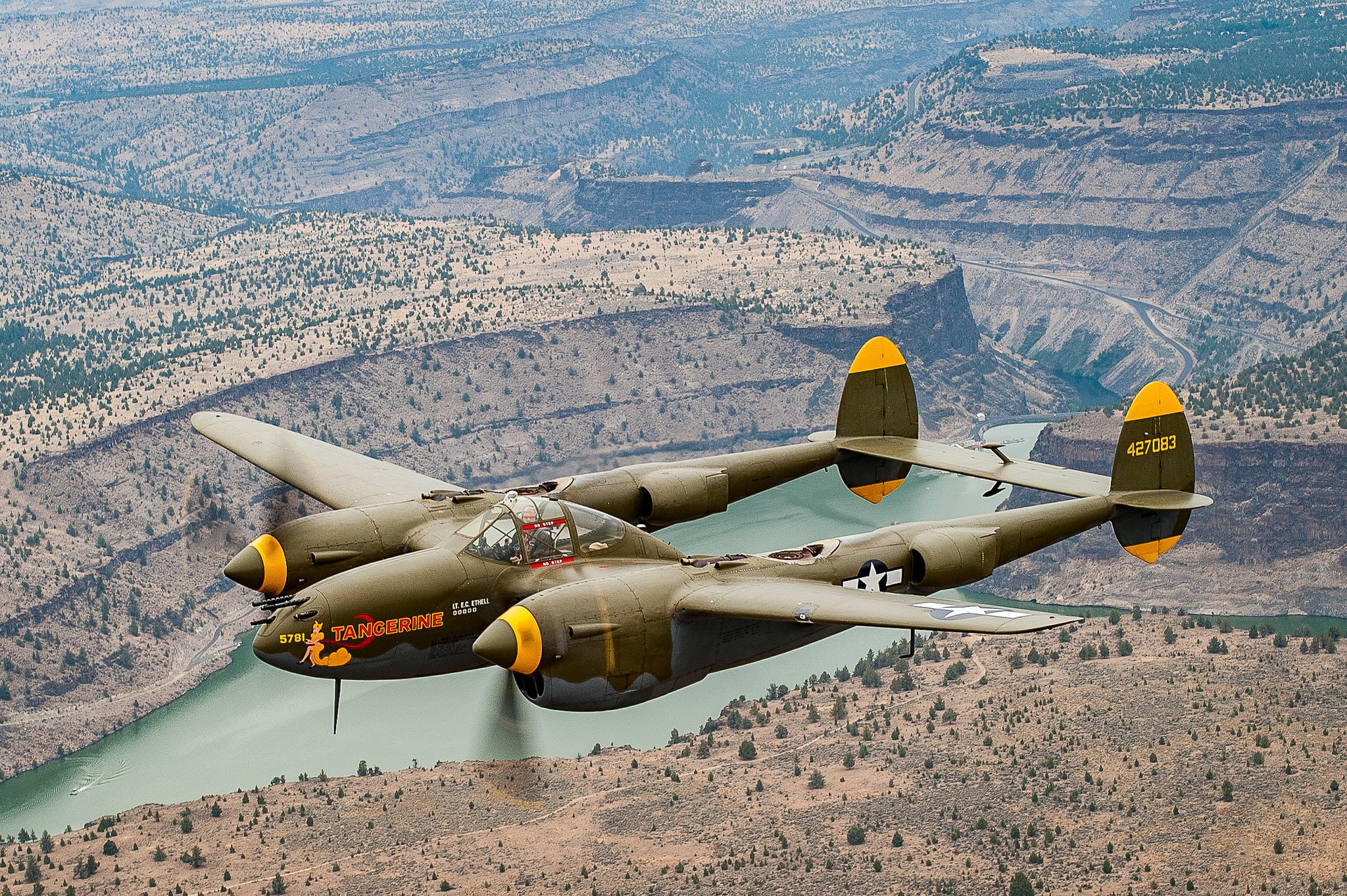 P-38 Lightning "Tangerine" fighter airplane flying over canyon HD Wallpaper