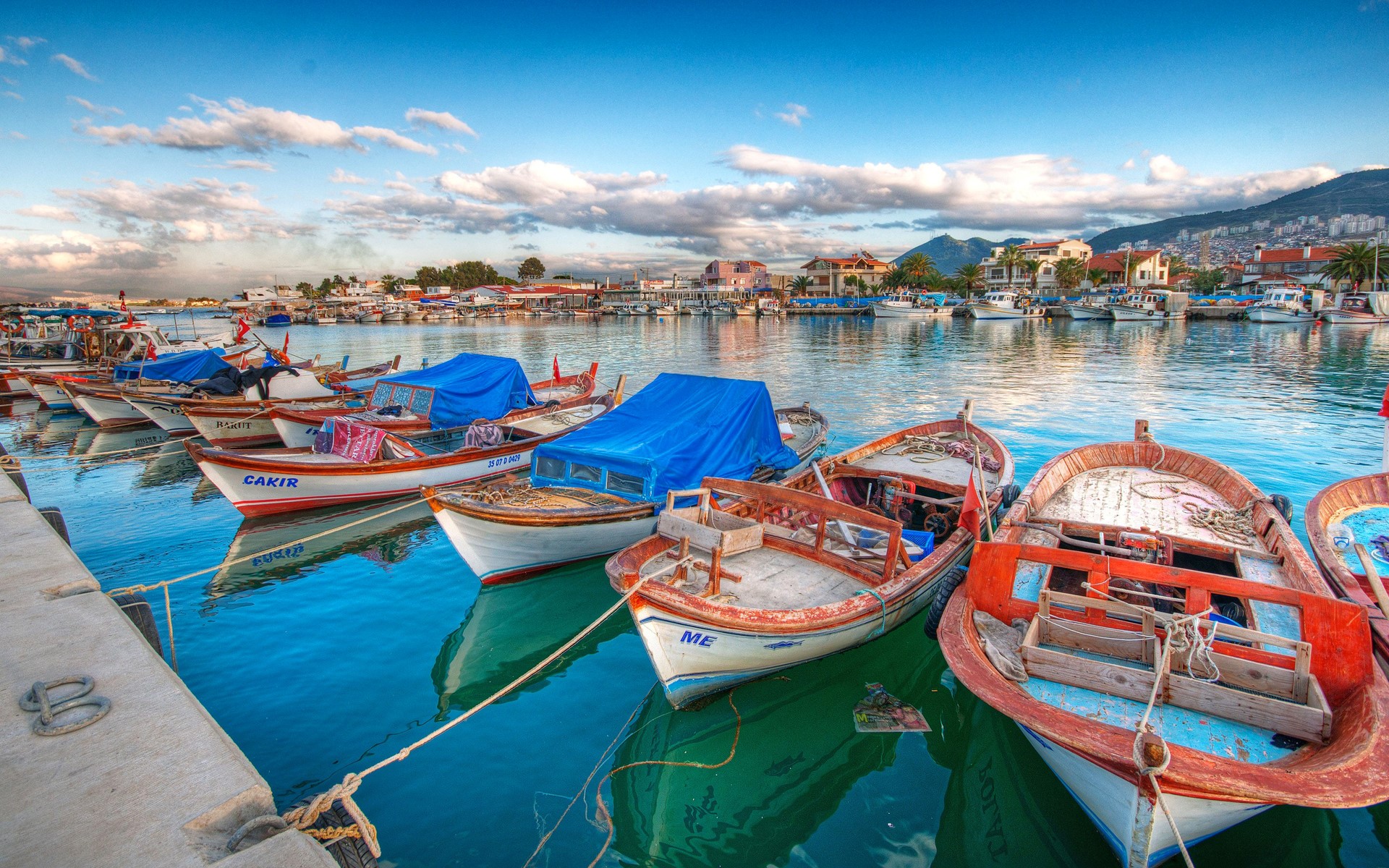 Boats docked in a harbor with a town in the background HD Wallpaper
