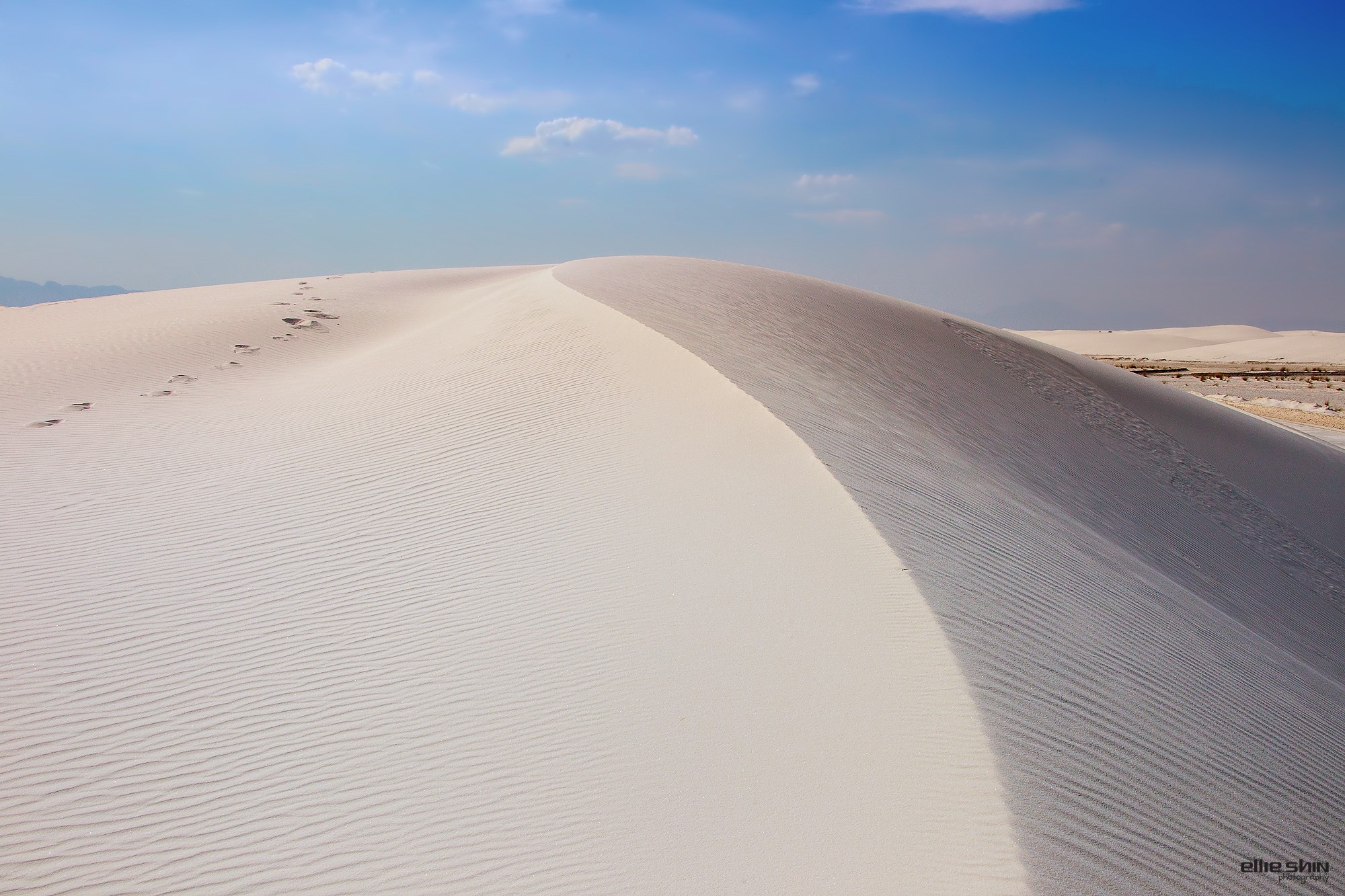 Footprints on a sand dune under a blue sky HD Wallpaper