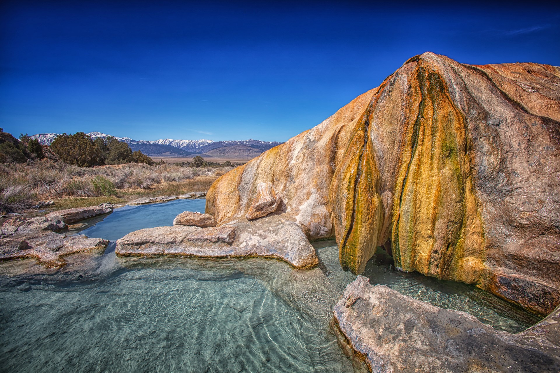 Hot springs with travertine rock formation and mountains HD Wallpaper