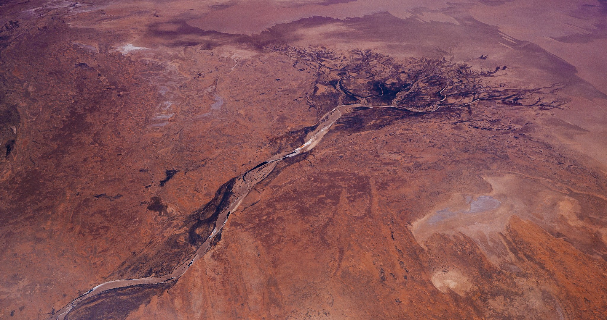 Aerial view of a dry riverbed in a desert landscape HD Wallpaper