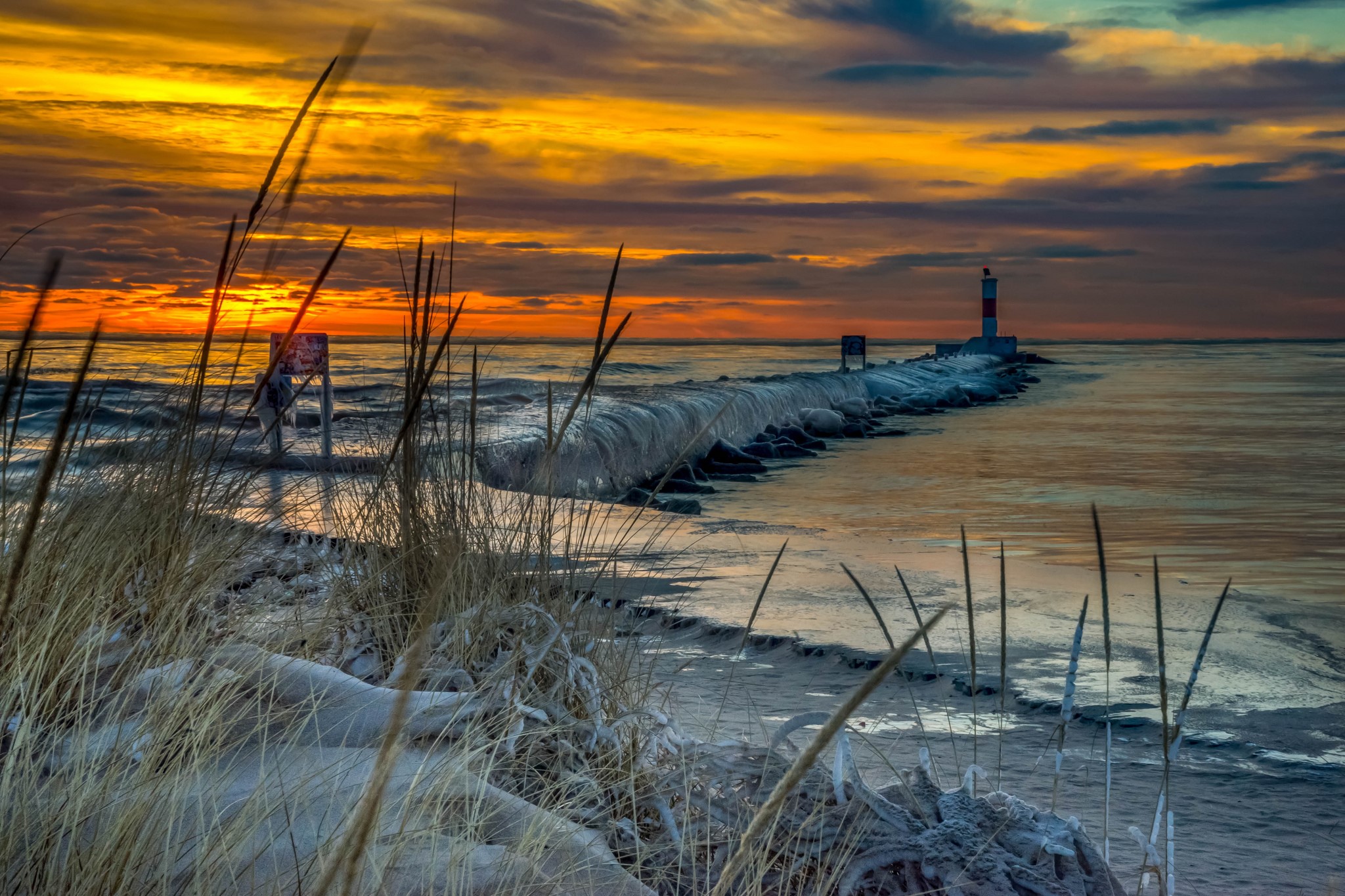 Lighthouse on a frozen pier at sunset HD Wallpaper
