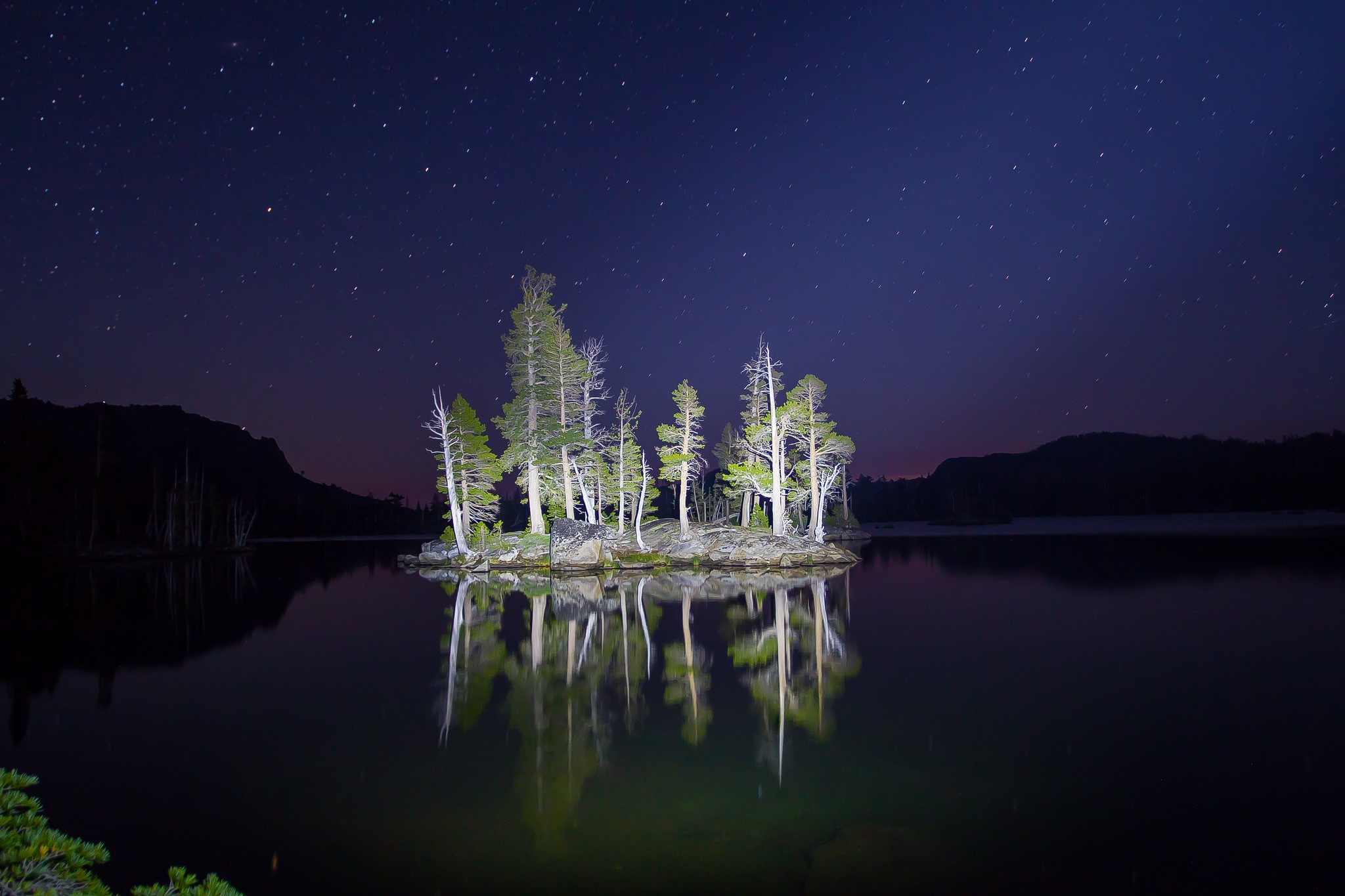 Island with trees on a lake at night under stars HD Wallpaper