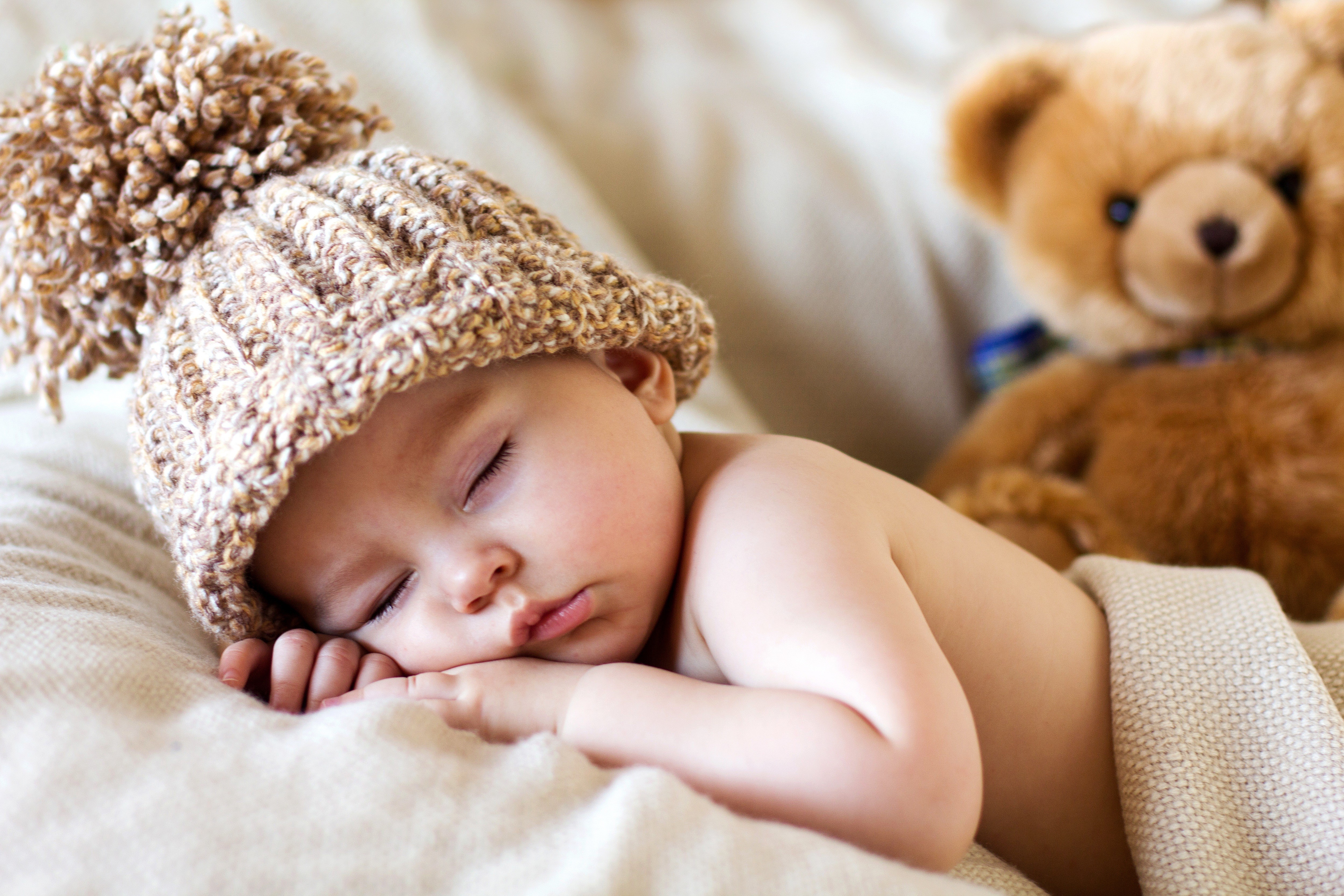 Baby sleeping with teddy bear and winter hat HD Wallpaper