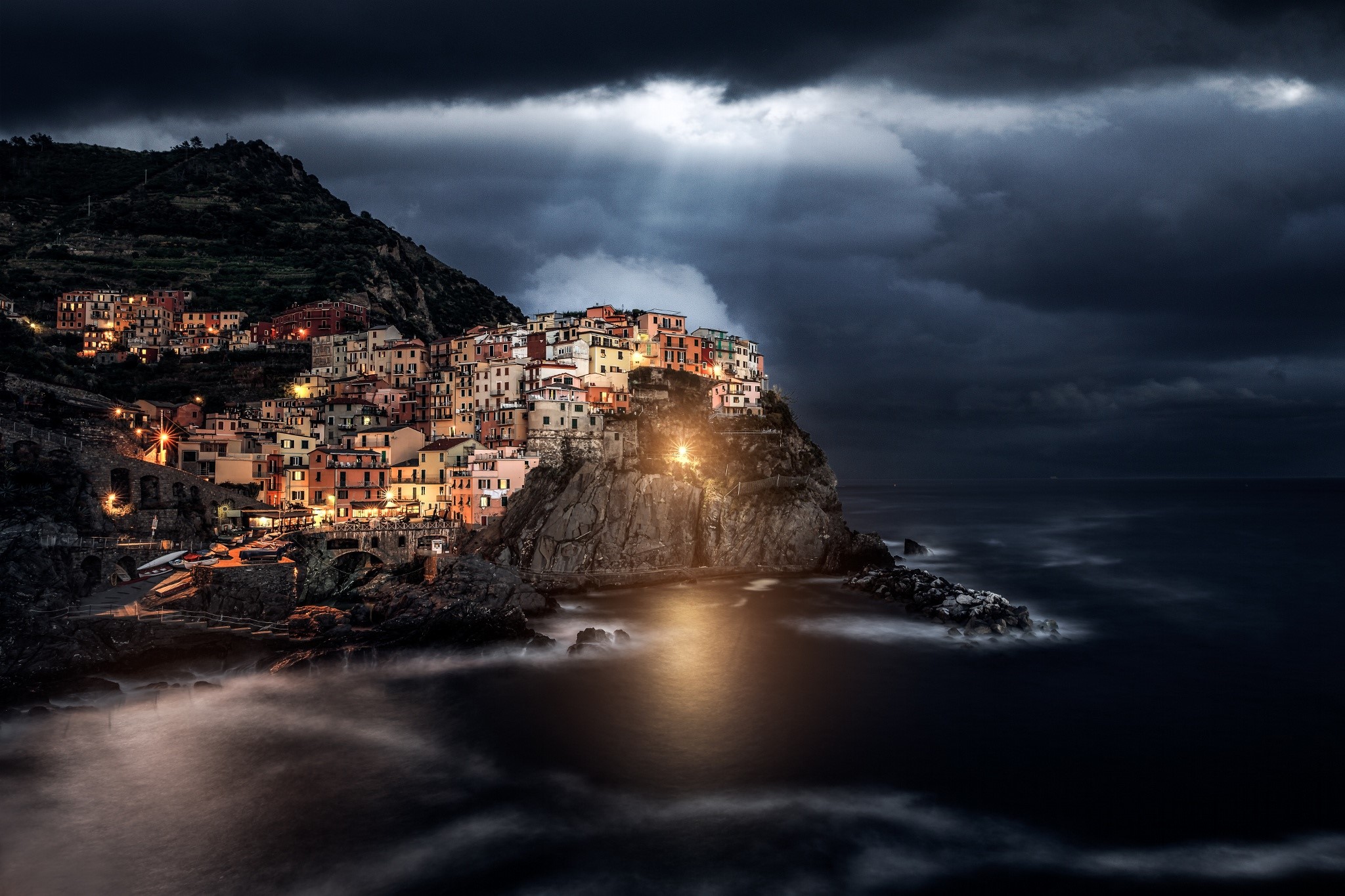 Manarola village on a rocky coast at night under thunderclouds HD Wallpaper