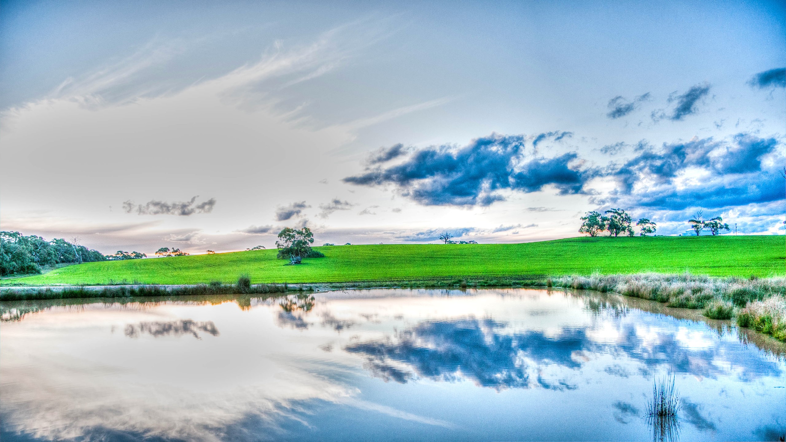 Lake and green hills under a cloudy sky HD Wallpaper