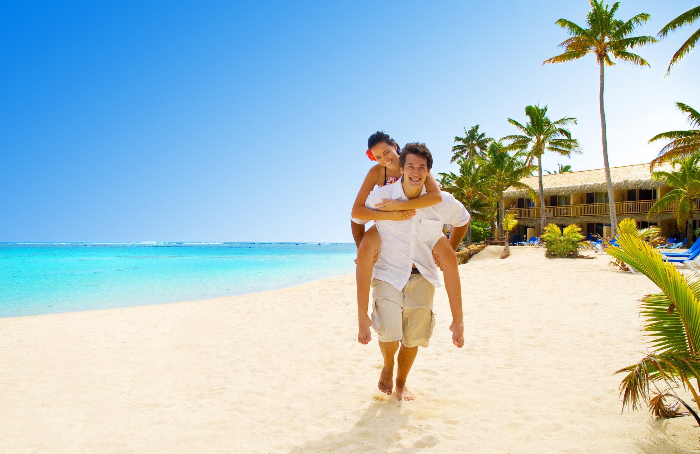 Couple piggybacking on a tropical beach HD Wallpaper