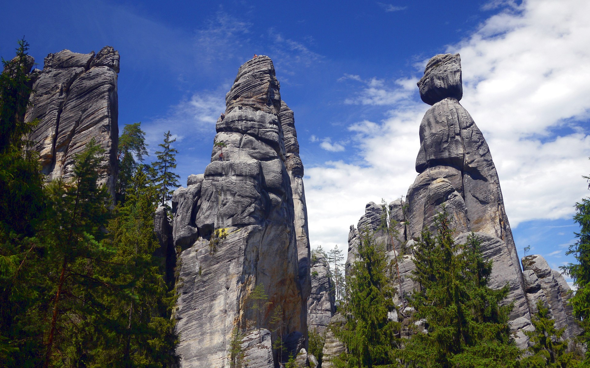 Tall rock formations with trees under a blue sky HD Wallpaper