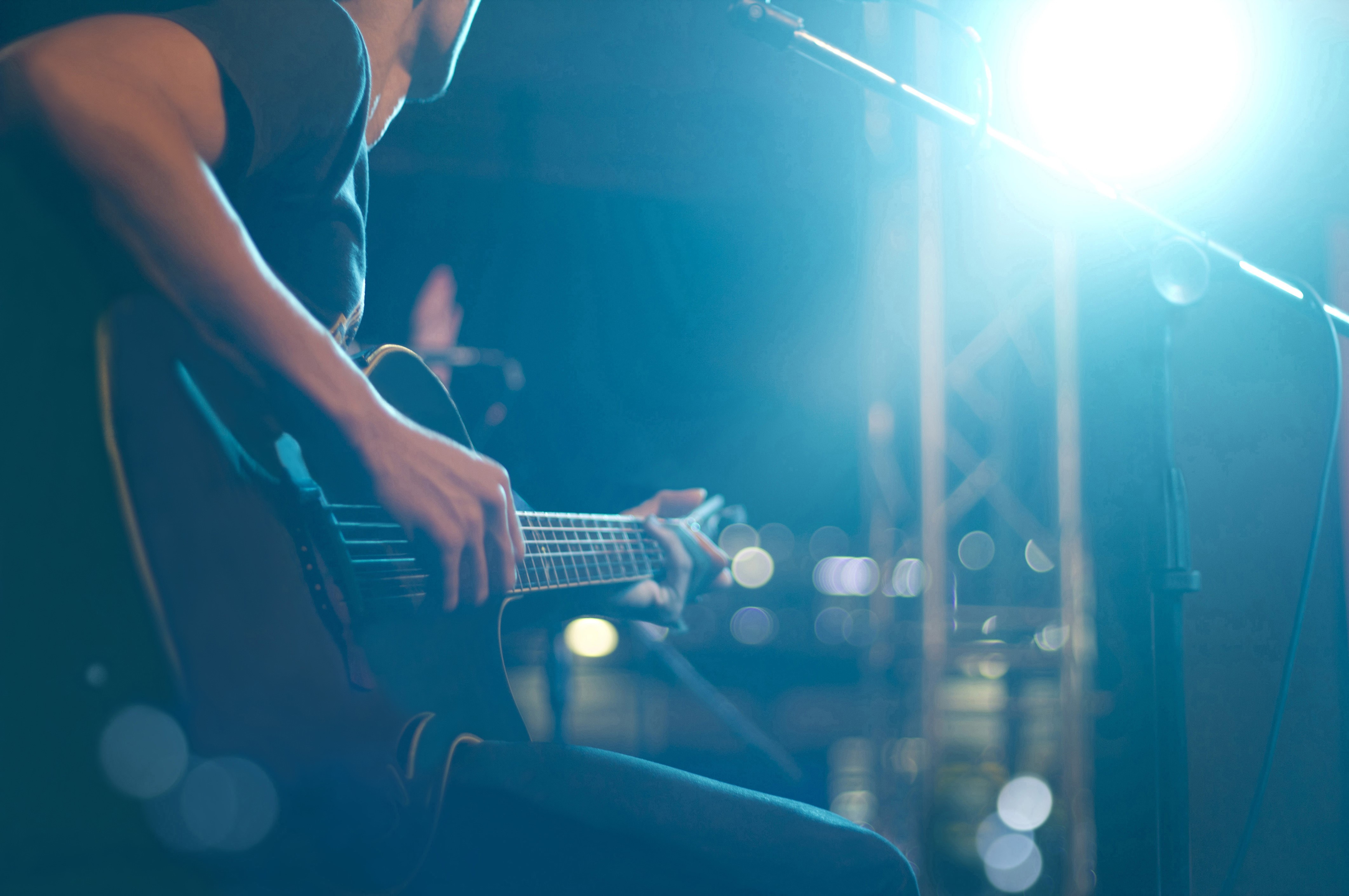 Man playing guitar on stage with blue lighting HD Wallpaper